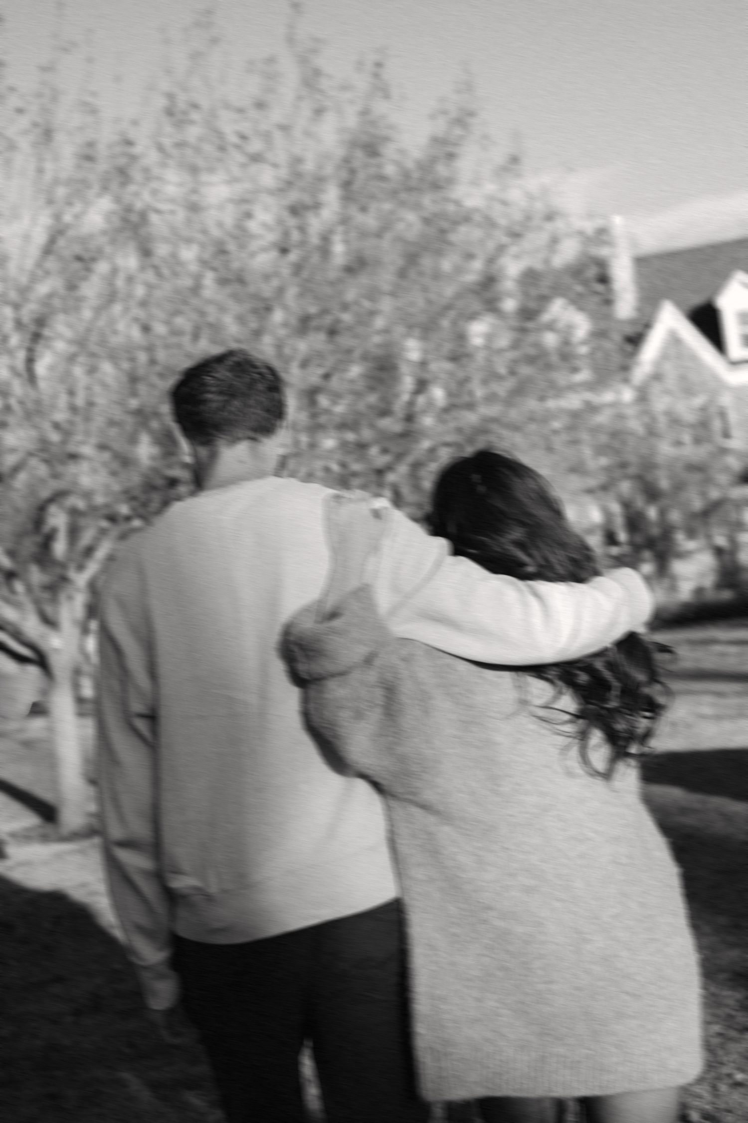 A sequence of black and white photos showing two people walking together outdoors on a sunny day.