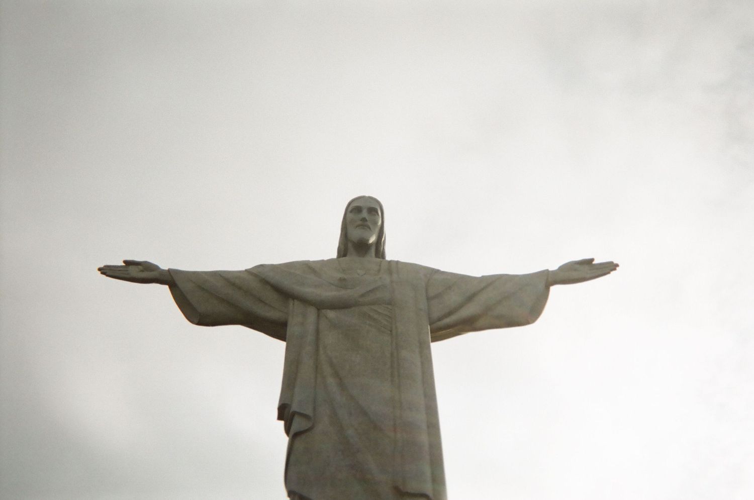 Close-up view of Christ the Redeemer statue's outstretched arms against cloudy sky in Rio.