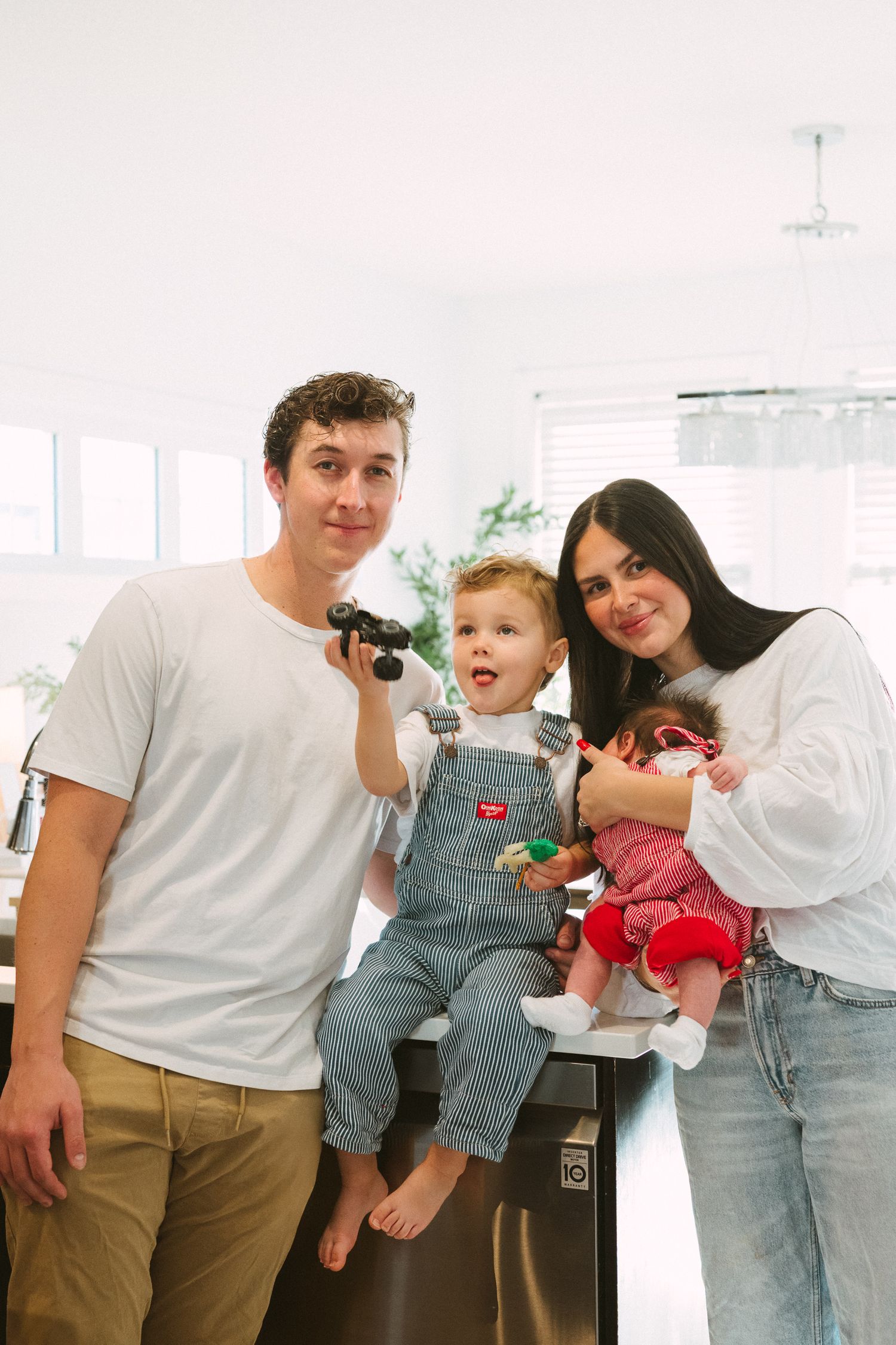 A family in matching white shirts and khaki pants poses together in a bright indoor setting.