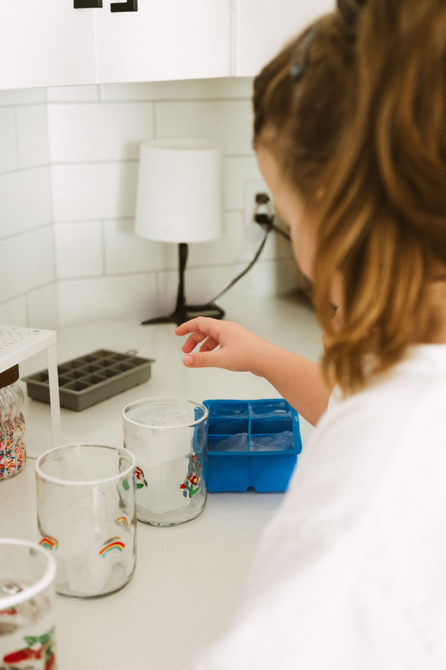 A sequence of photos showing someone conducting a science experiment with clear measuring cups and blue containers.