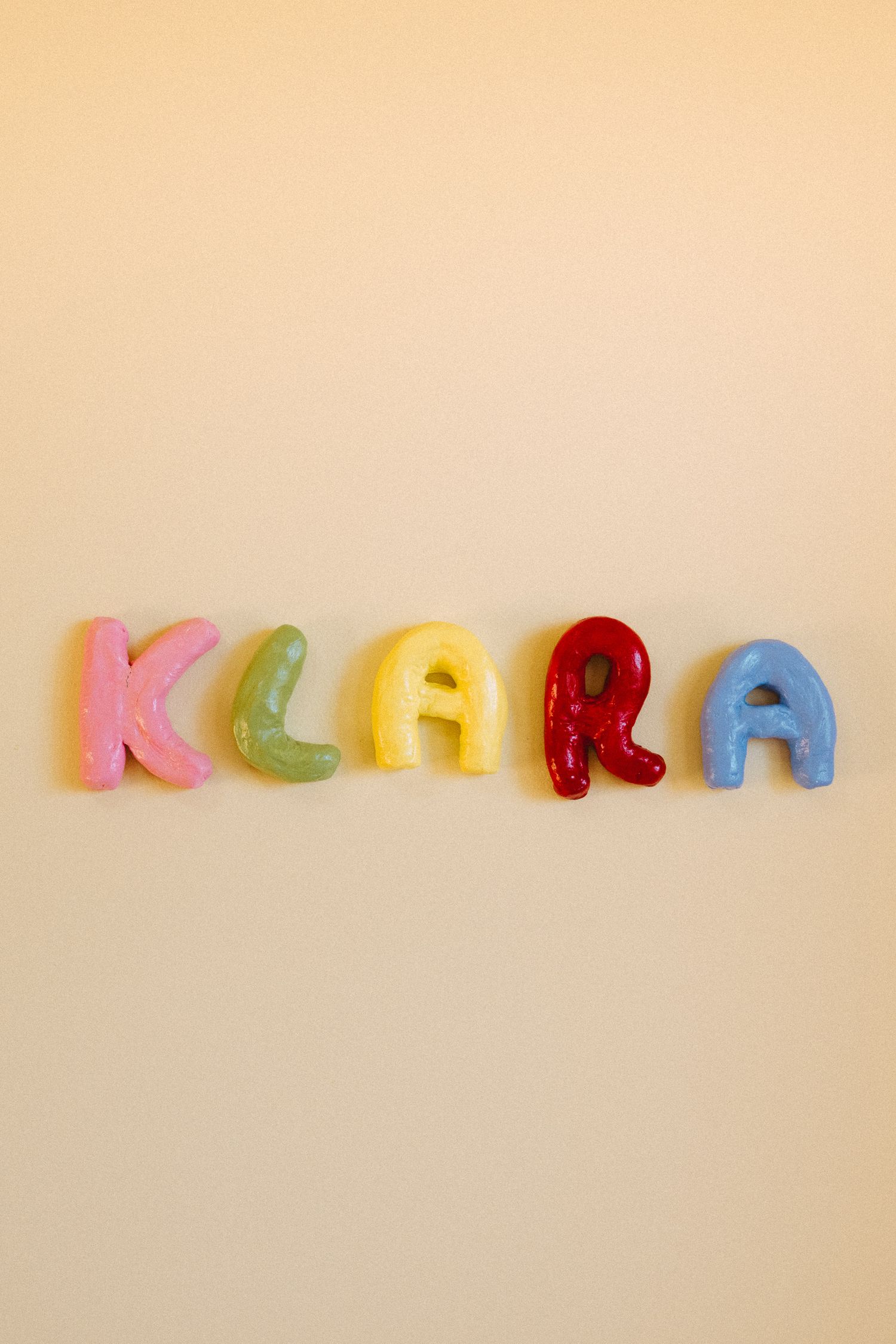 Colorful letter magnets spelling KLARA against beige background.