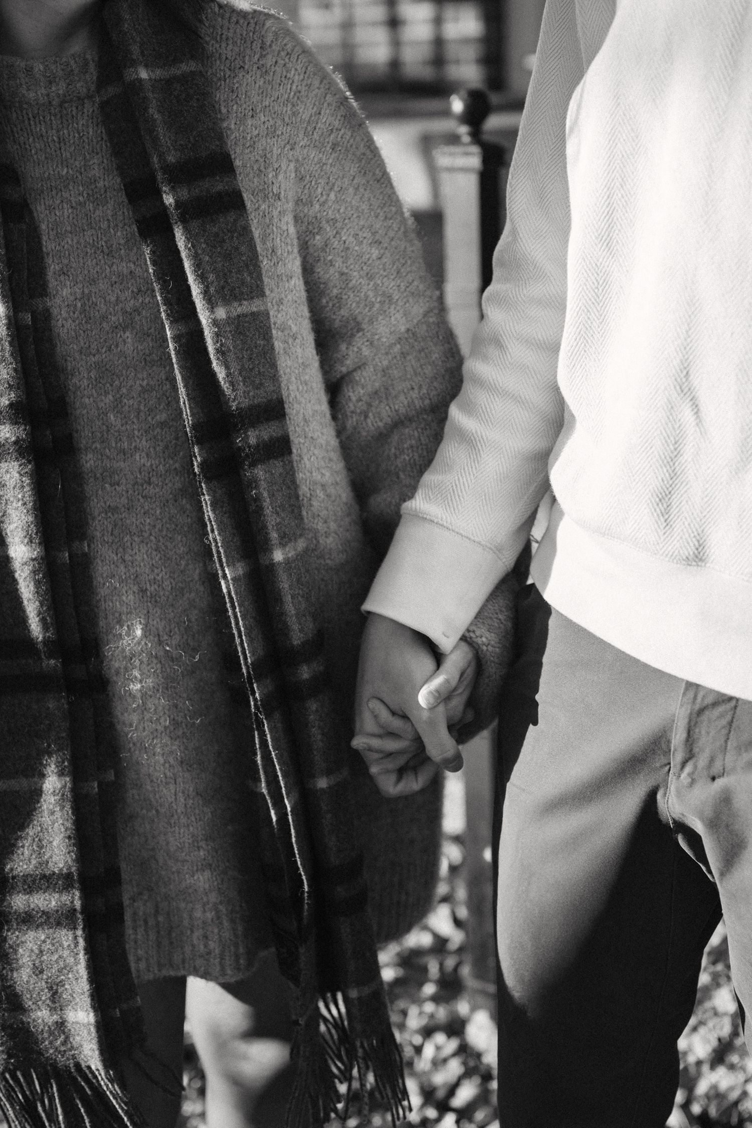 Black and white close-up photo showing two people holding hands in an intimate moment.