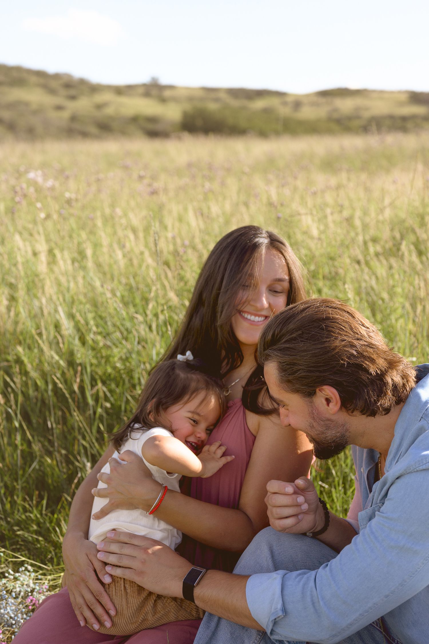 A tender family moment captured in a golden field during sunset.
