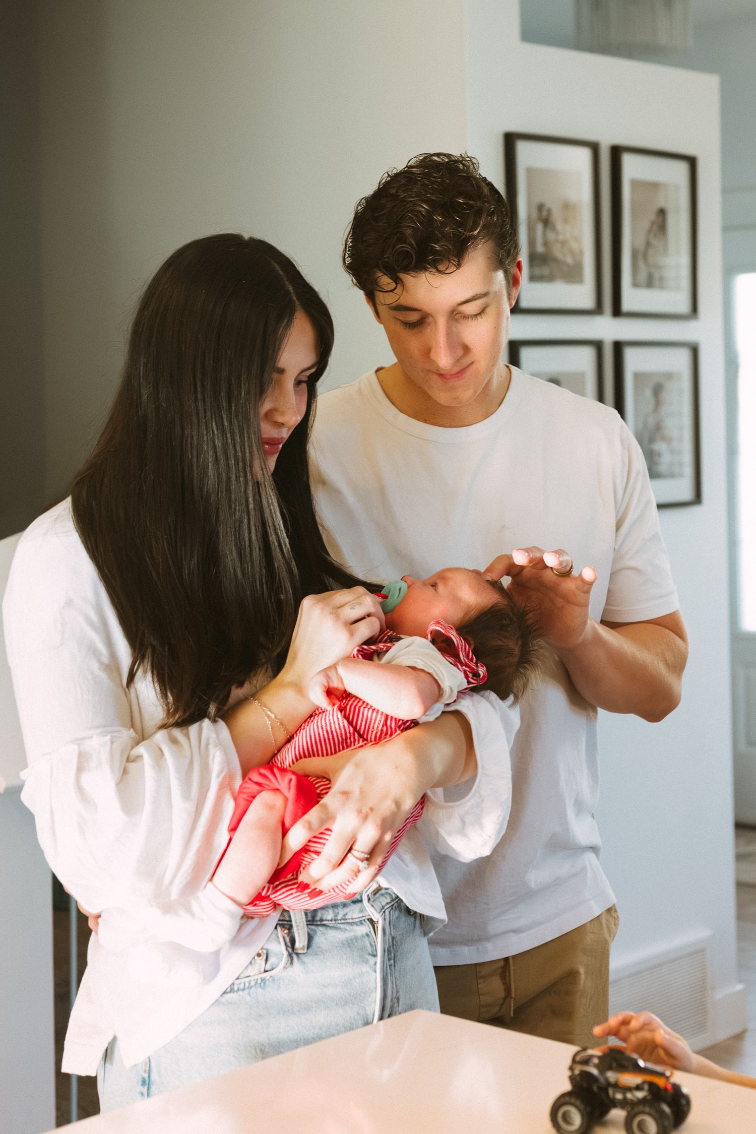 A series of tender moments between parents and their newborn baby in a bright, modern home setting.