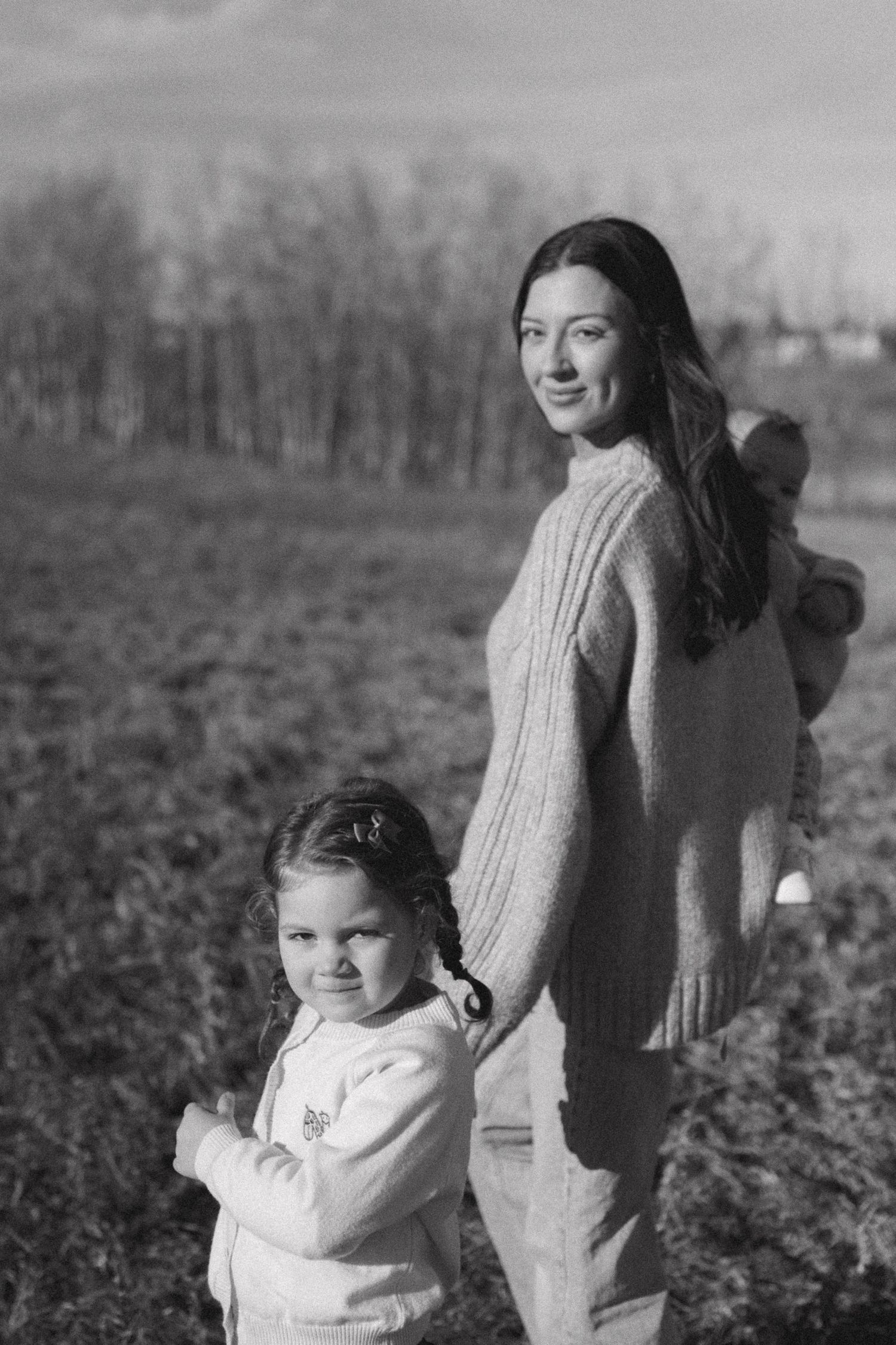 A black and white photo series shows a mother and young child walking together through a field.