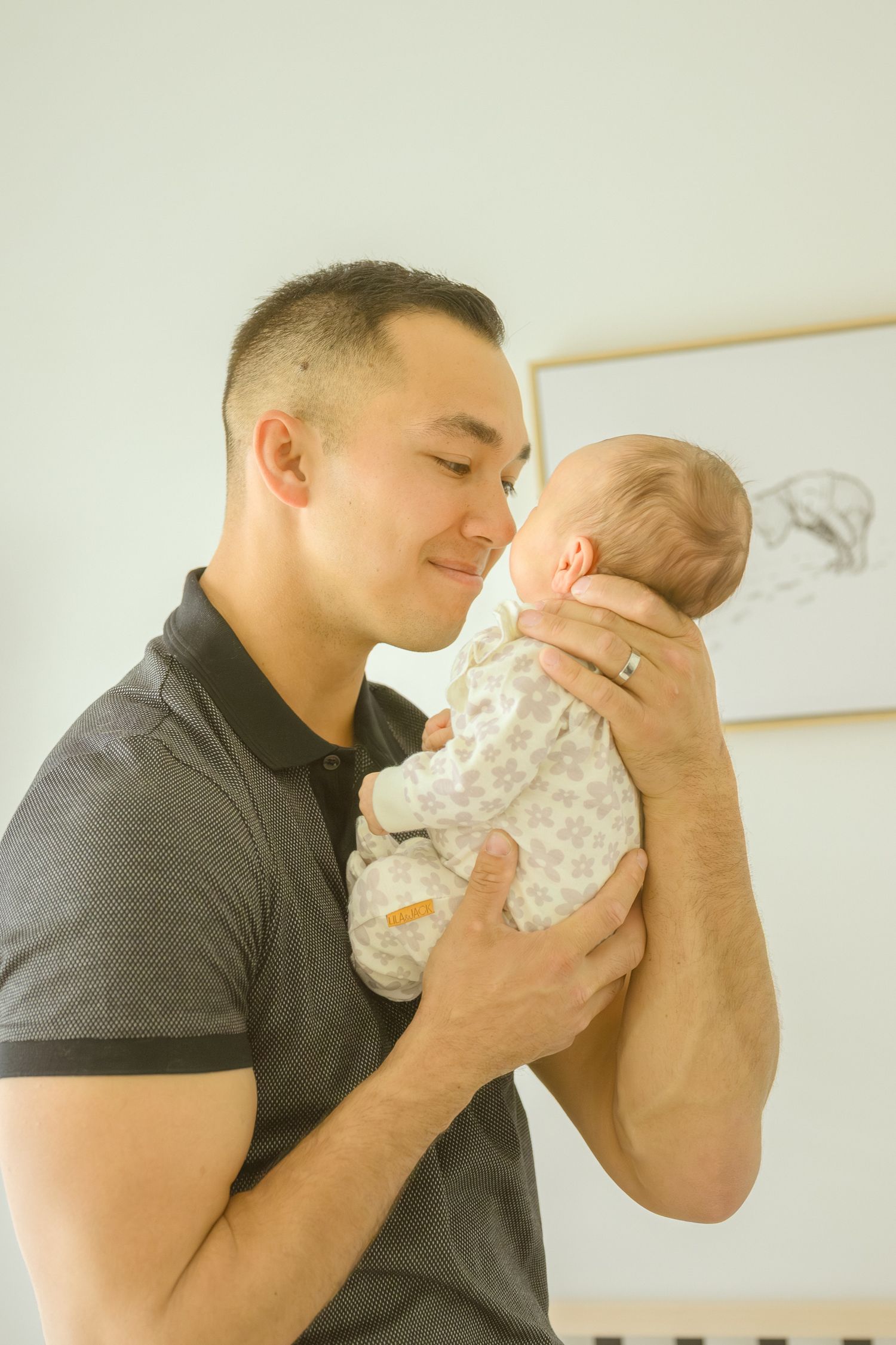 A tender moment between father and baby in a softly lit nursery with minimal decor.