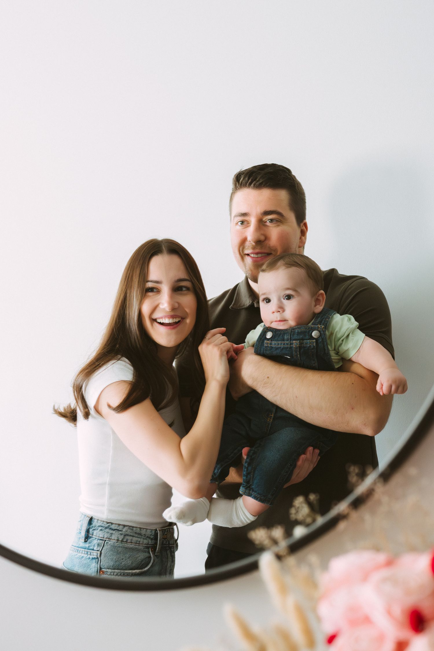 Family having fun and laughing together while taking selfies in a mirror at home.