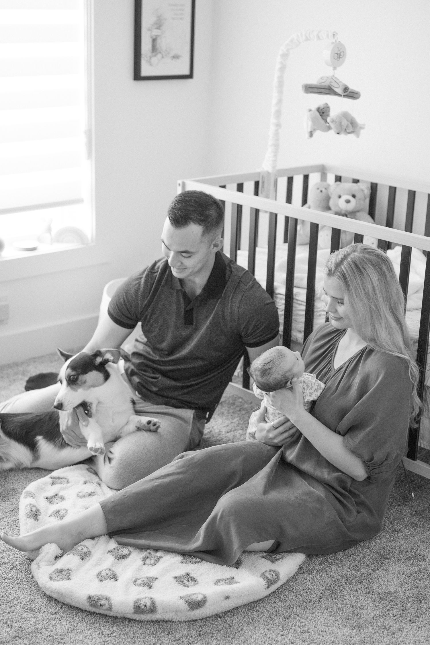 Family relaxing on a butterfly-patterned nursing pillow in a nursery with natural light.
