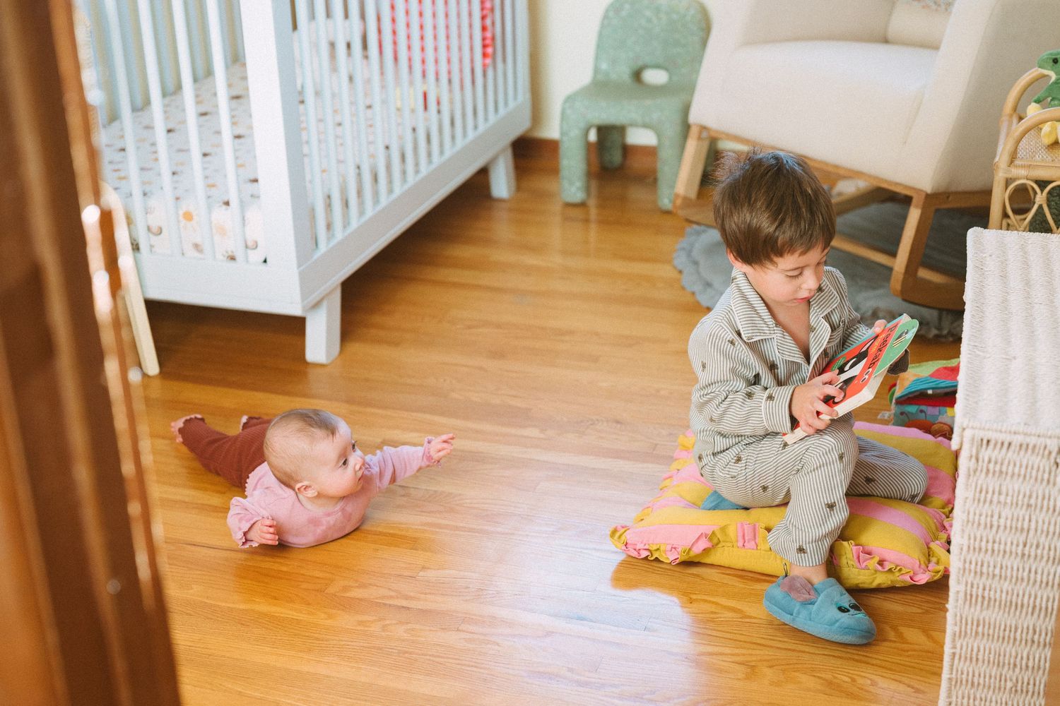 Candid playtime scene on wooden floor with scattered toys and white furniture.