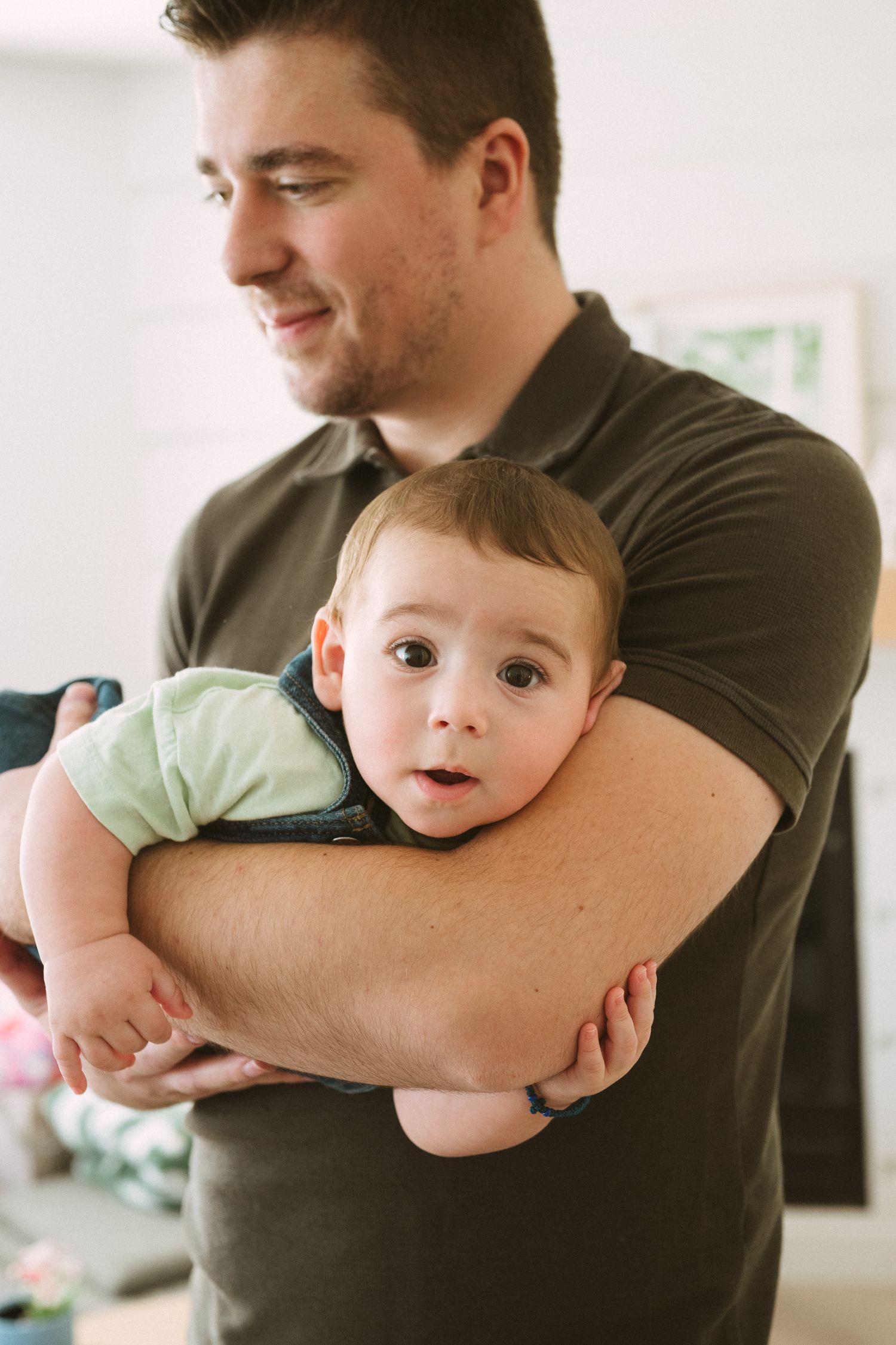 Adult in black shirt holding and cuddling with baby wearing light green outfit.