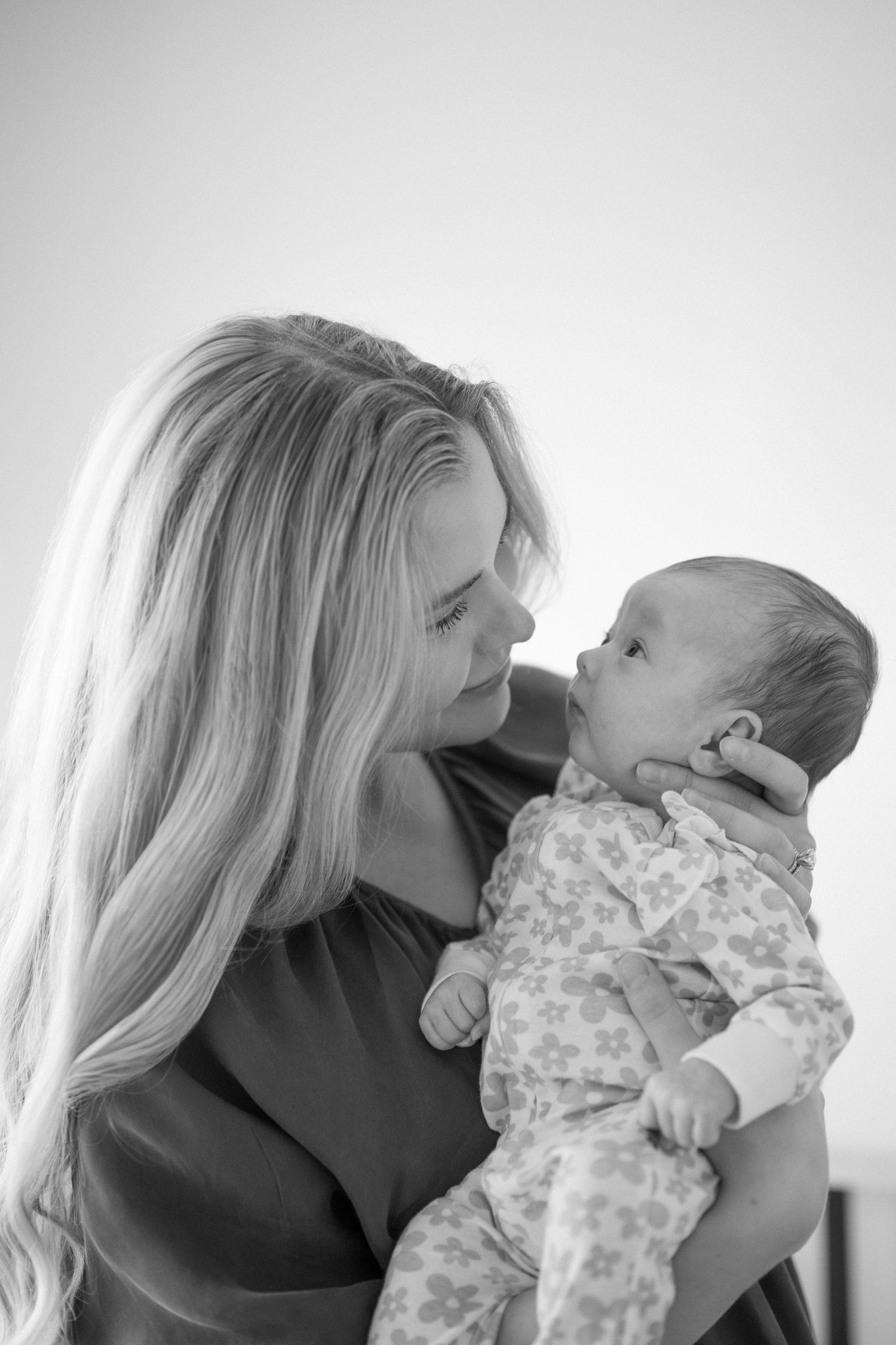 Black and white portrait of tender moment with baby in floral outfit.