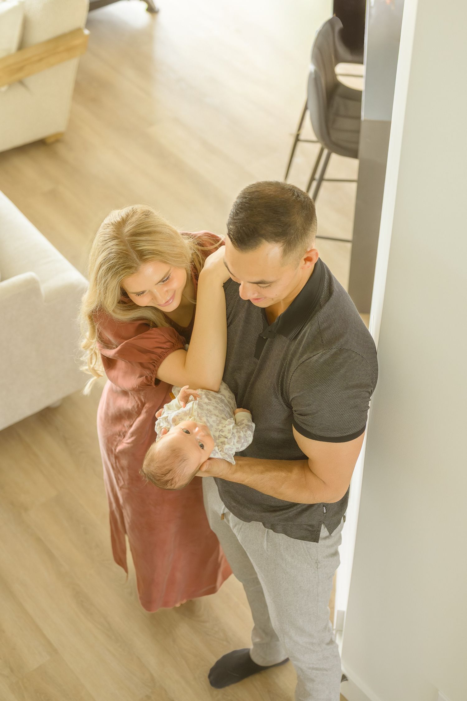 Parents in casual clothes sharing tender moment with newborn baby.