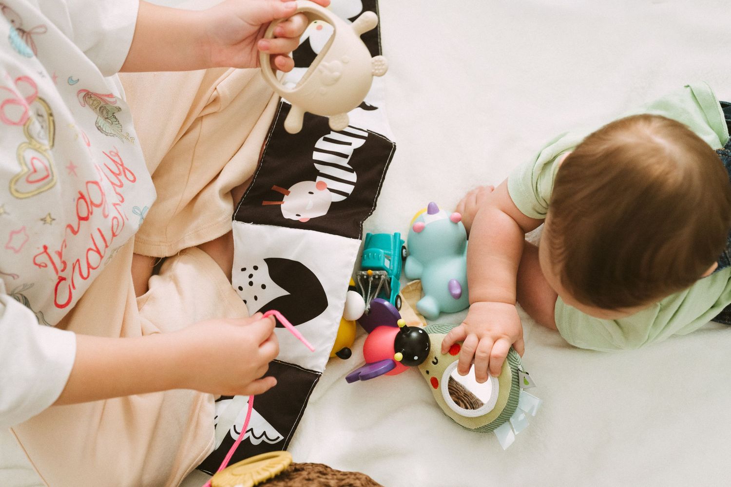 Multiple hands work together to decorate cookies with colorful frosting and sprinkles during a baking activity.