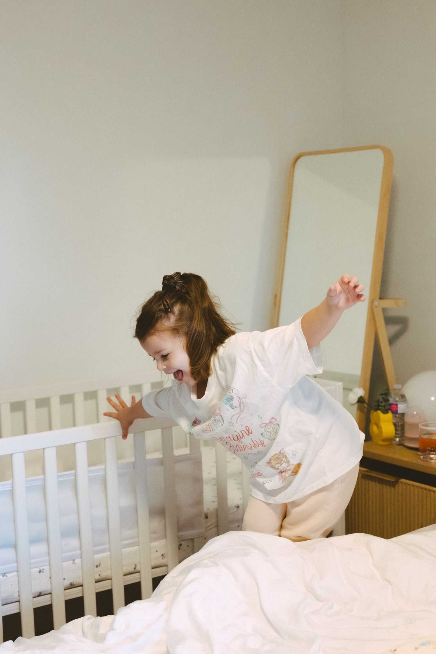 A sequence of photos showing someone playfully hiding under white bedsheets in a bedroom with a white headboard.