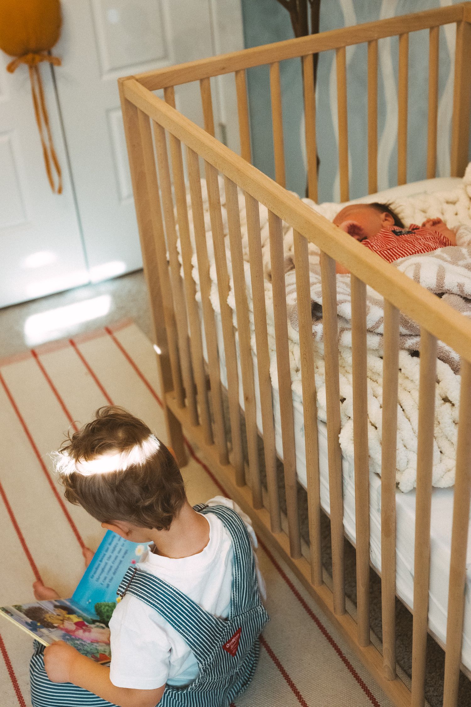 Child in white shirt leans over wooden railing to look at something below.