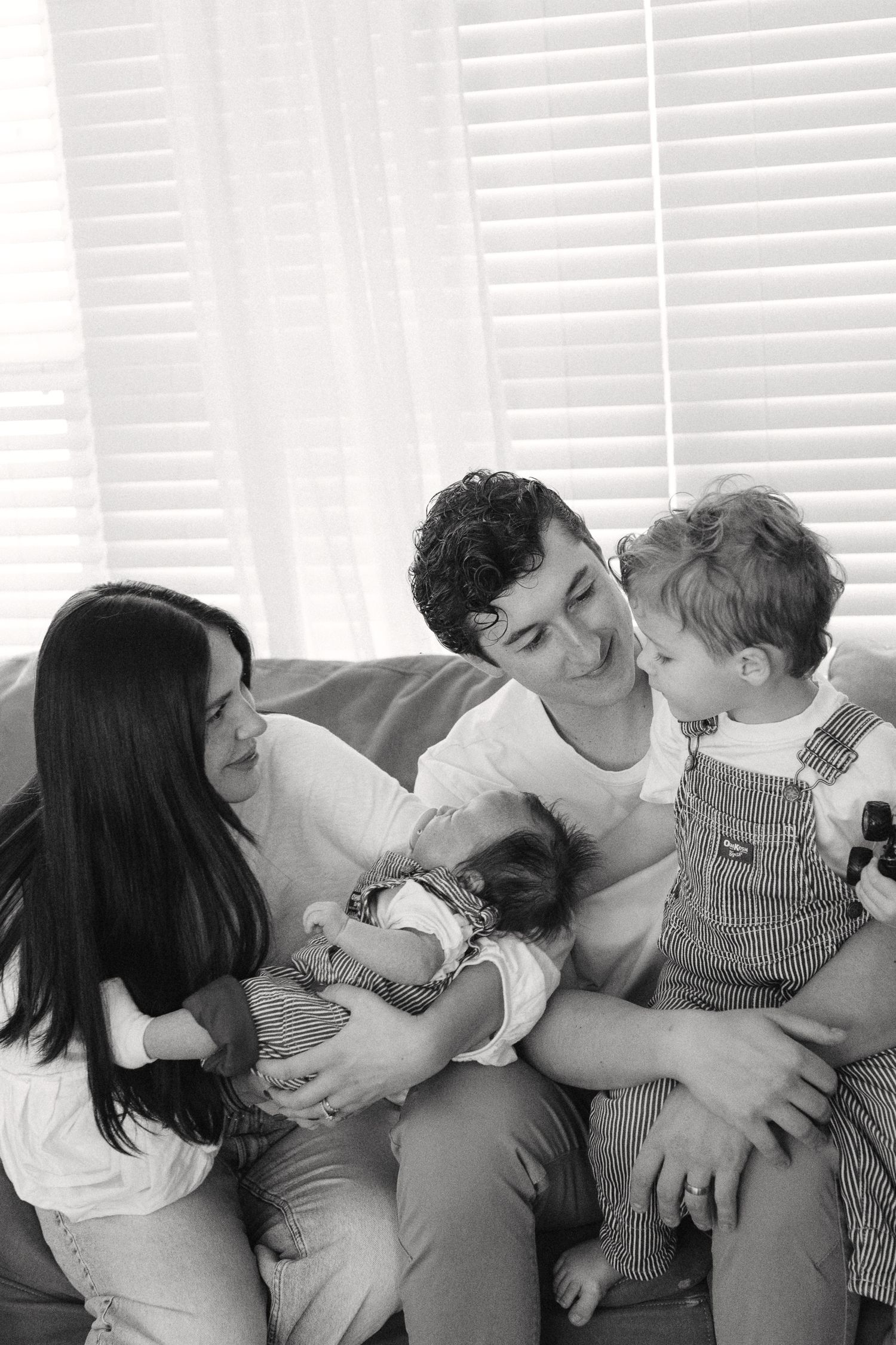 A sequence of loving family interactions captured in black and white on a comfortable couch.
