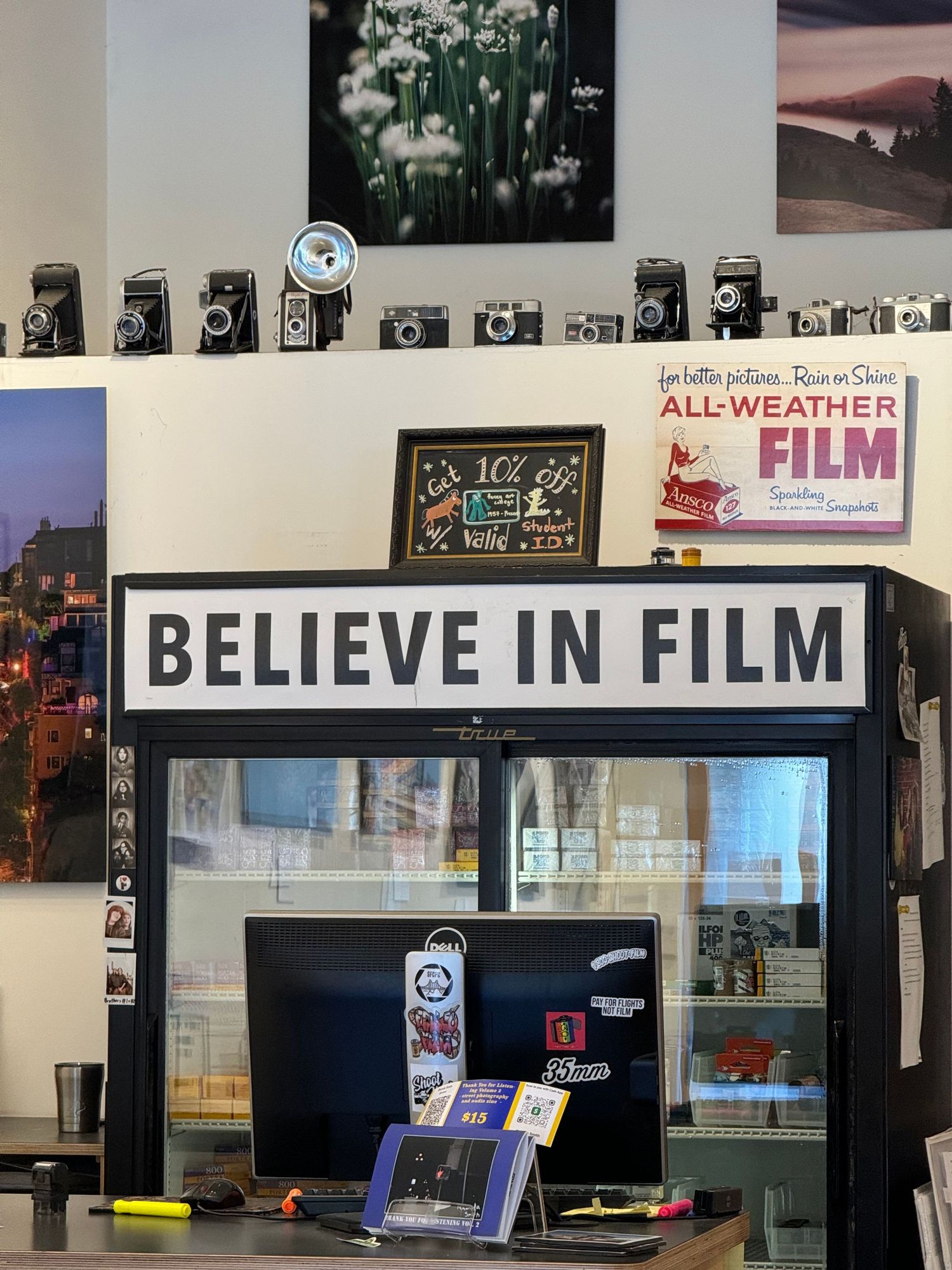 Interior of a photography shop with vintage cameras on display and a 'Believe in Film' sign.