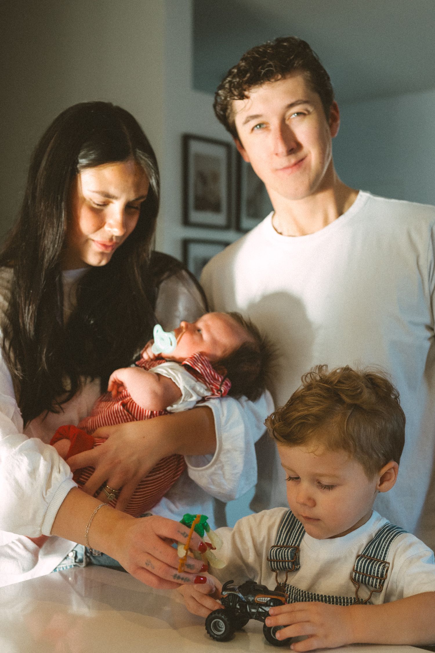 A family plays together with toys on a couch in a naturally lit living room.