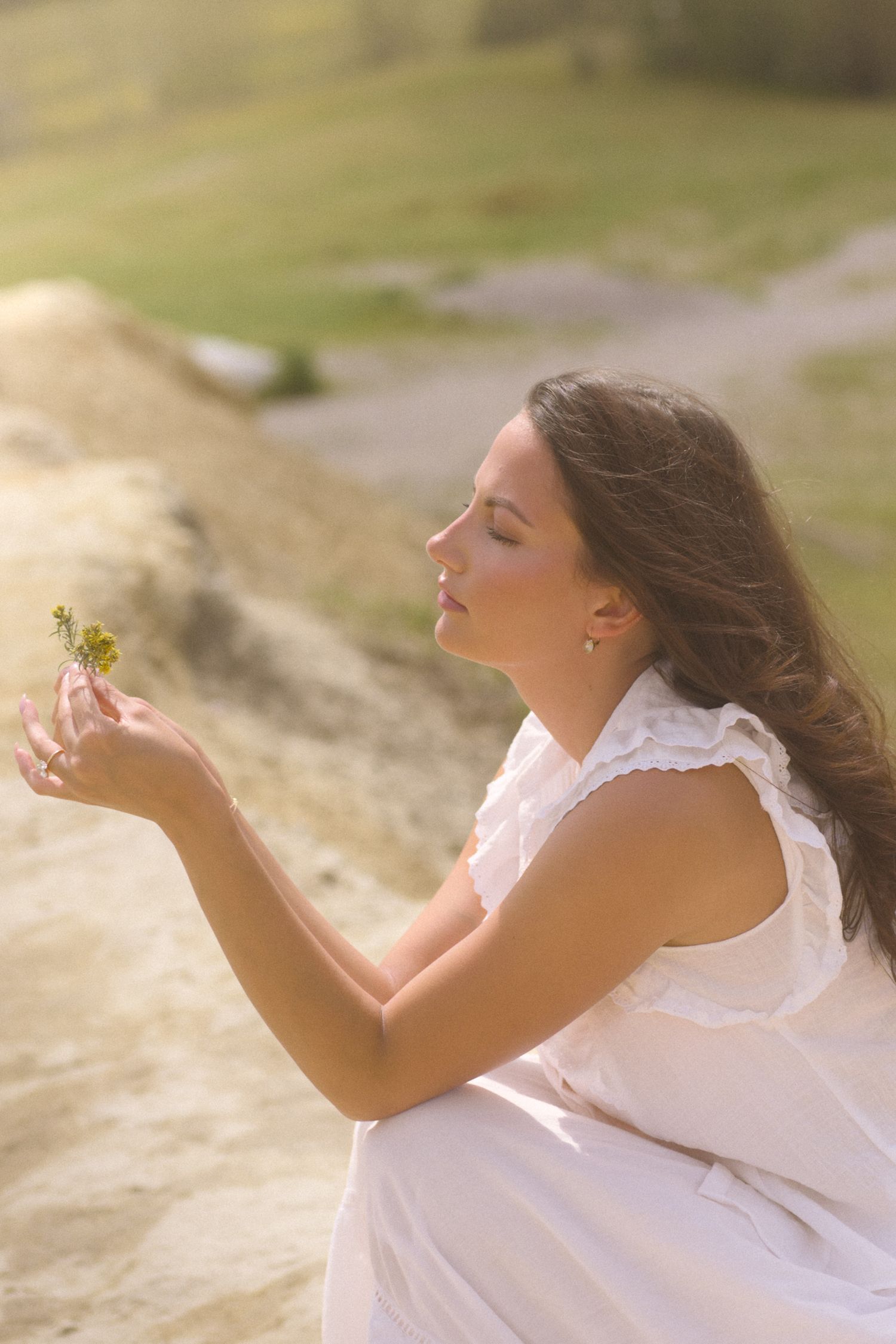 Someone in white lace gazes upward with closed eyes in warm sunlight.