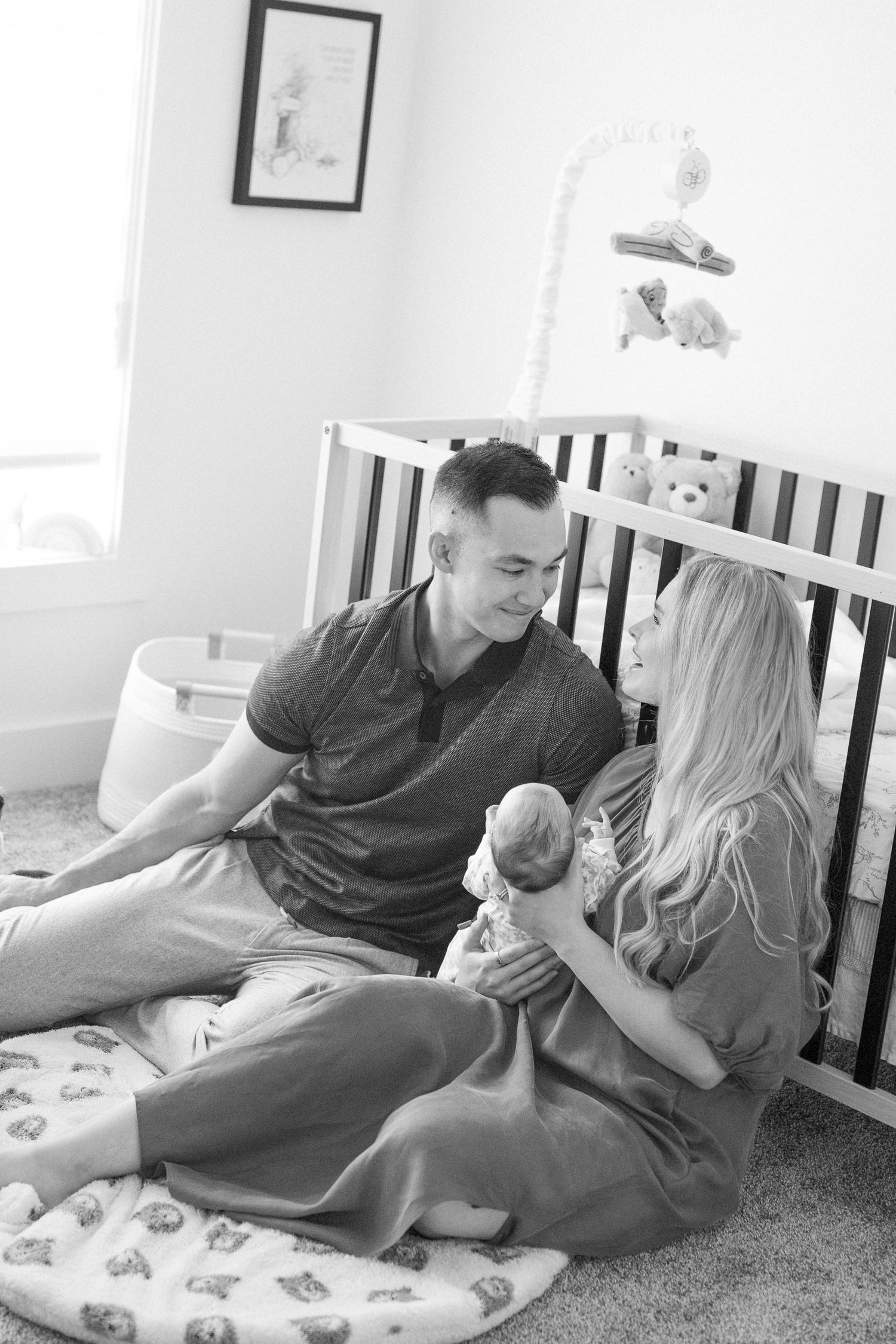Parents and baby sharing intimate moments on a nursing pillow in a bright nursery setting.
