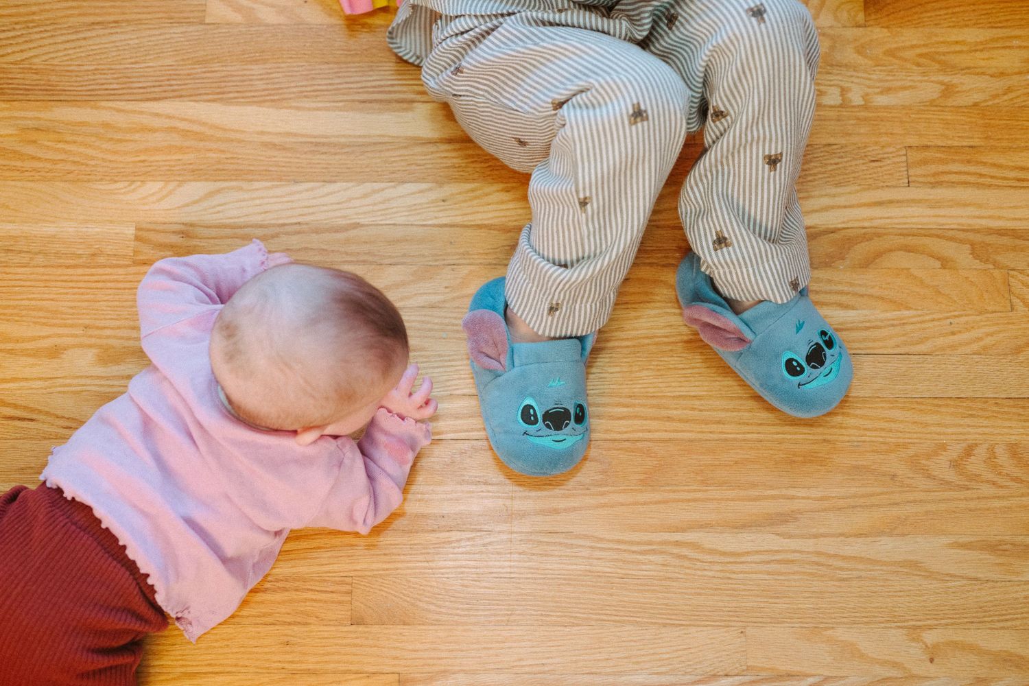 Overhead view of children playing on hardwood floor with various toys.