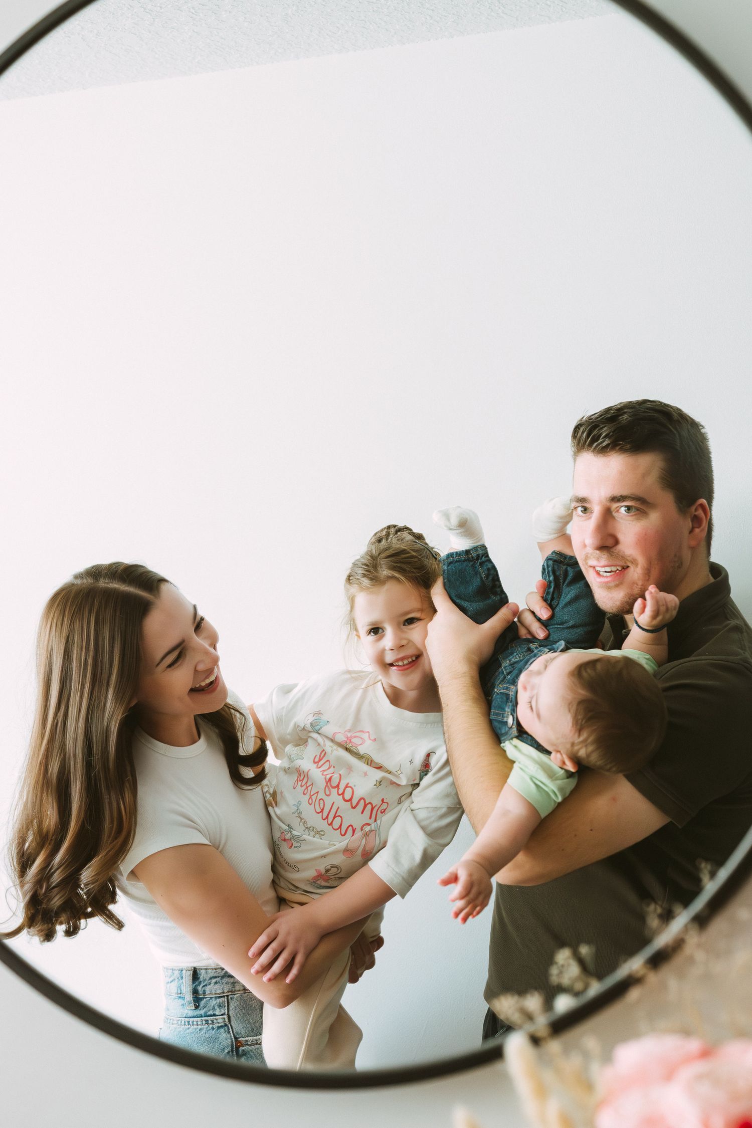 A series of mirror selfies showing tender family moments with a baby and parents at home.