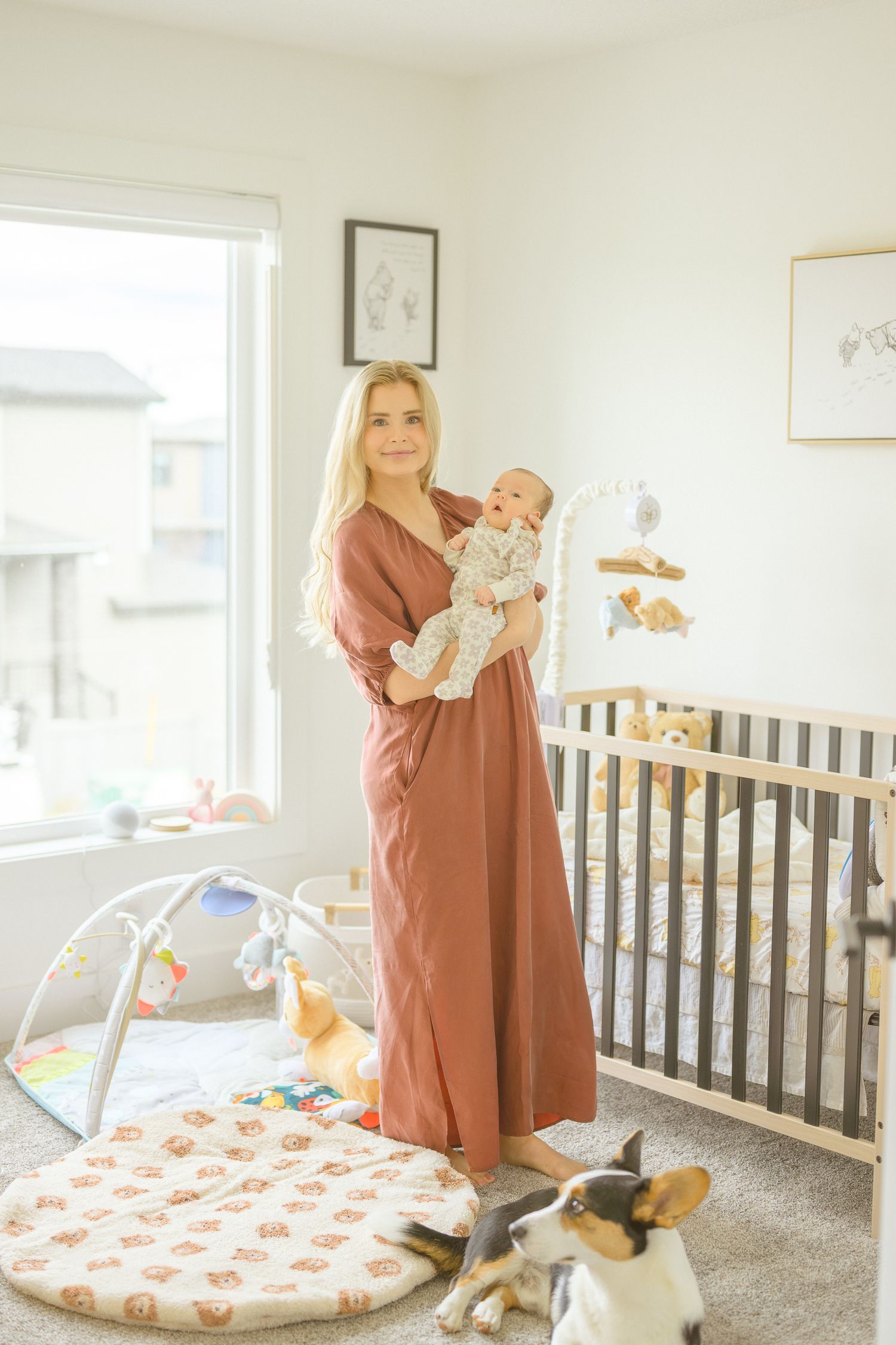 Nursery room with crib, play mat, and pet dog visible in bright natural light.