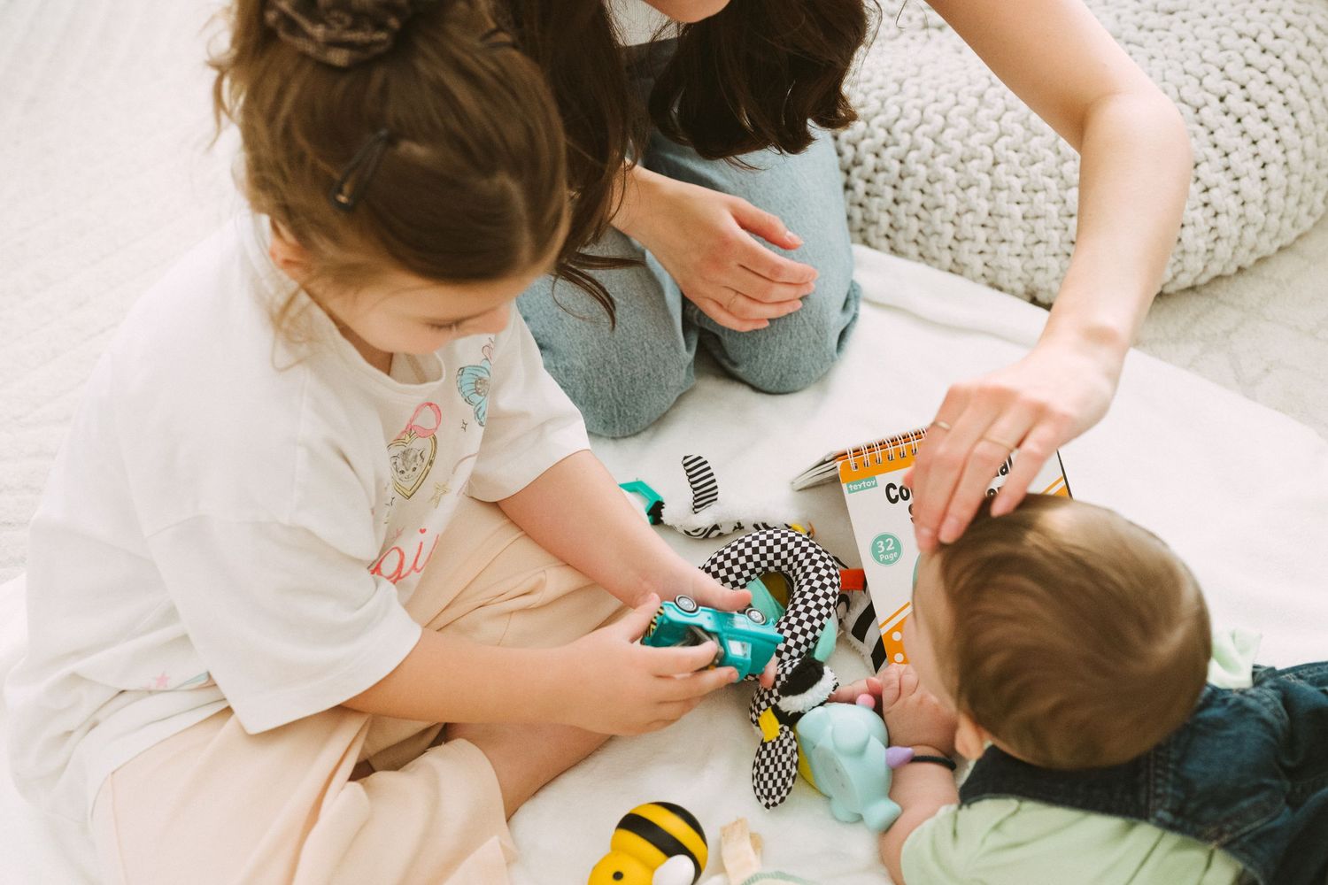 Children playing together with colorful toys on a comfortable cushioned surface.