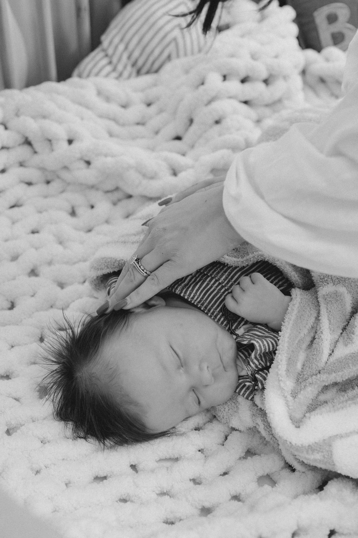Peaceful sleeping baby wrapped in white blanket on chunky knit texture.
