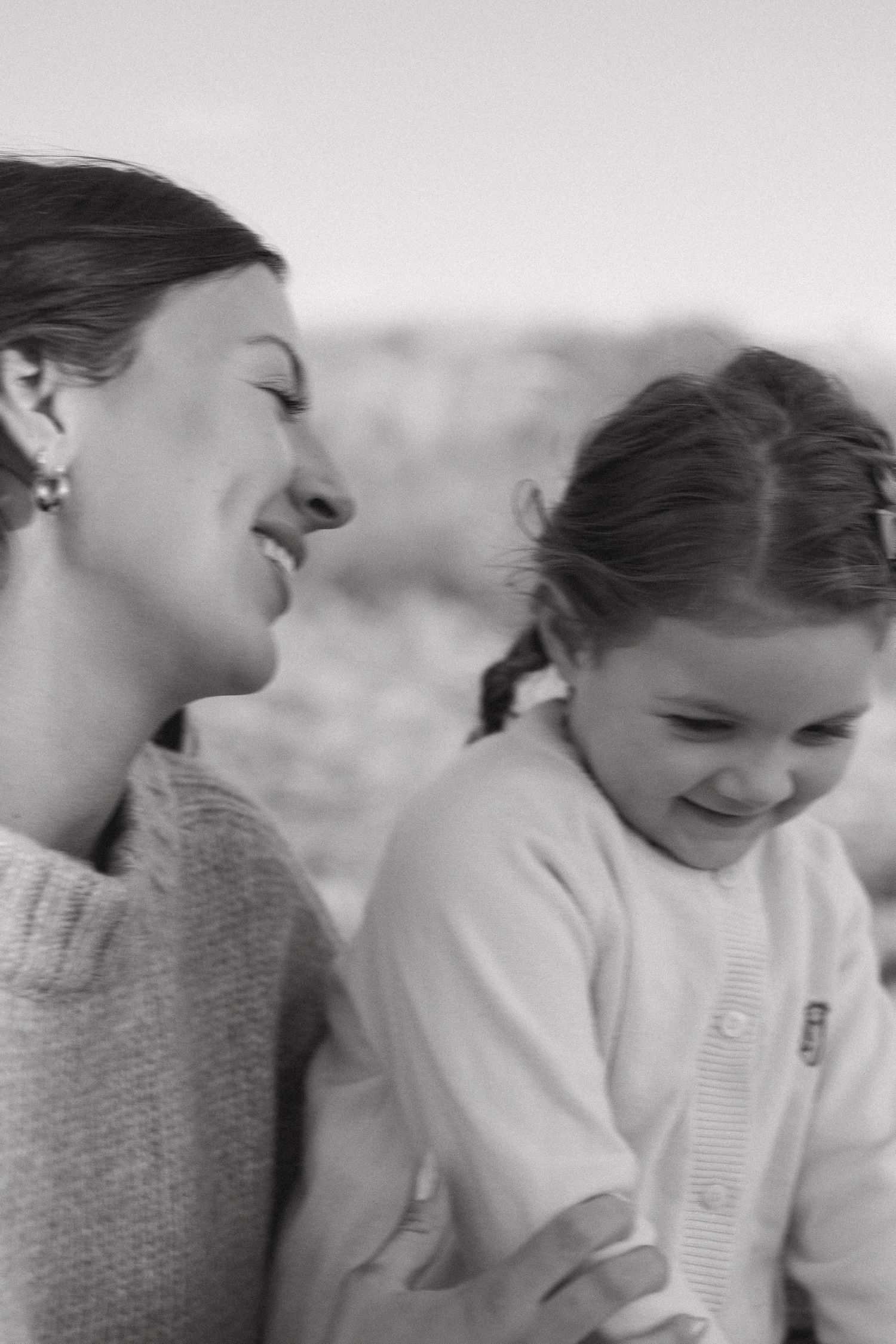 An intimate black and white candid moment showing joyful laughter and embraces outdoors.
