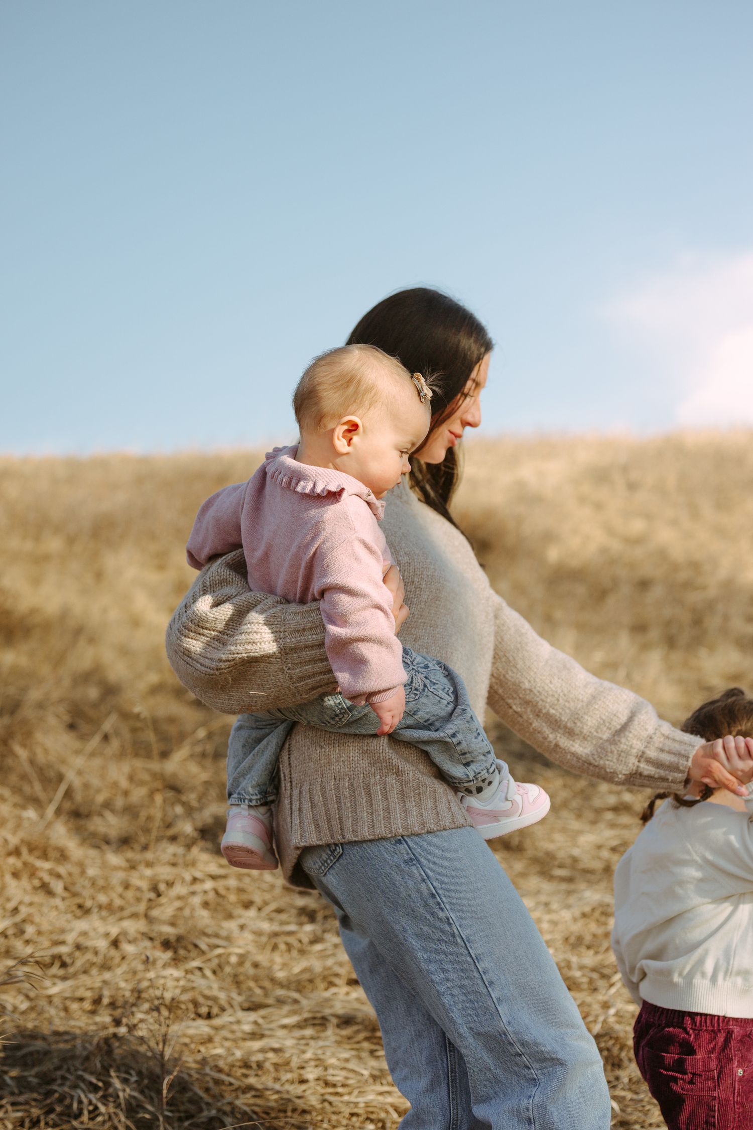 A candid outdoor scene of family bonding in a sunlit field with warm autumn tones.