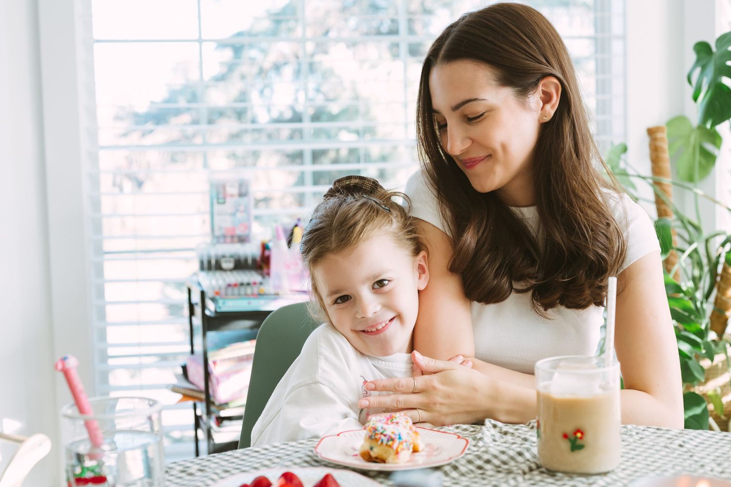 Casual breakfast scene at bright window with coffee and pastries on table.