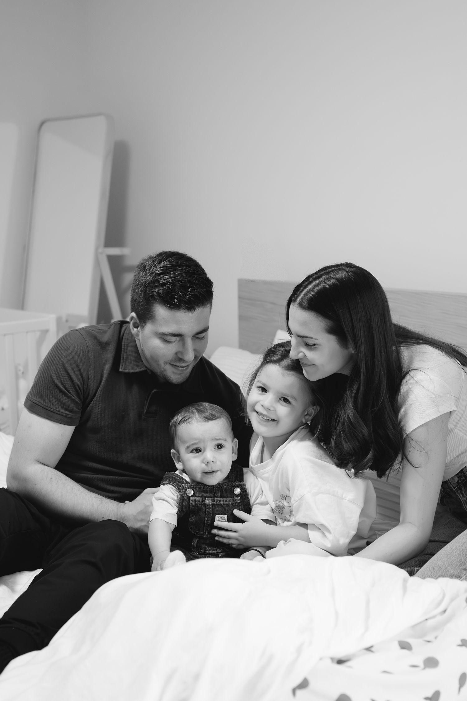 Black and white family lifestyle photos showing intimate moments together on a white bed.