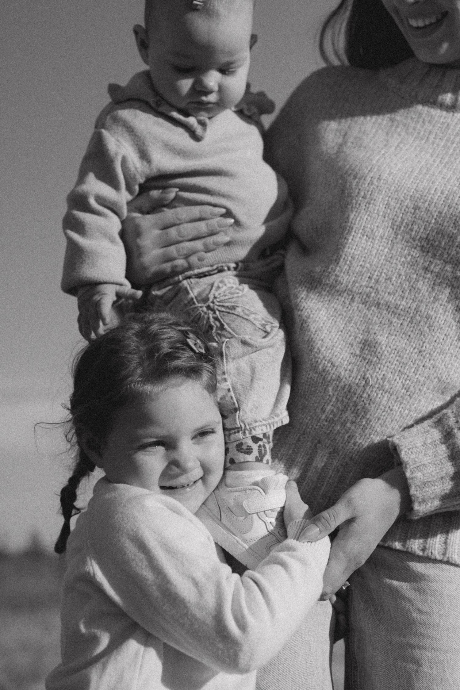 A series of black and white photos showing a baby being held and hugged in casual, candid moments.