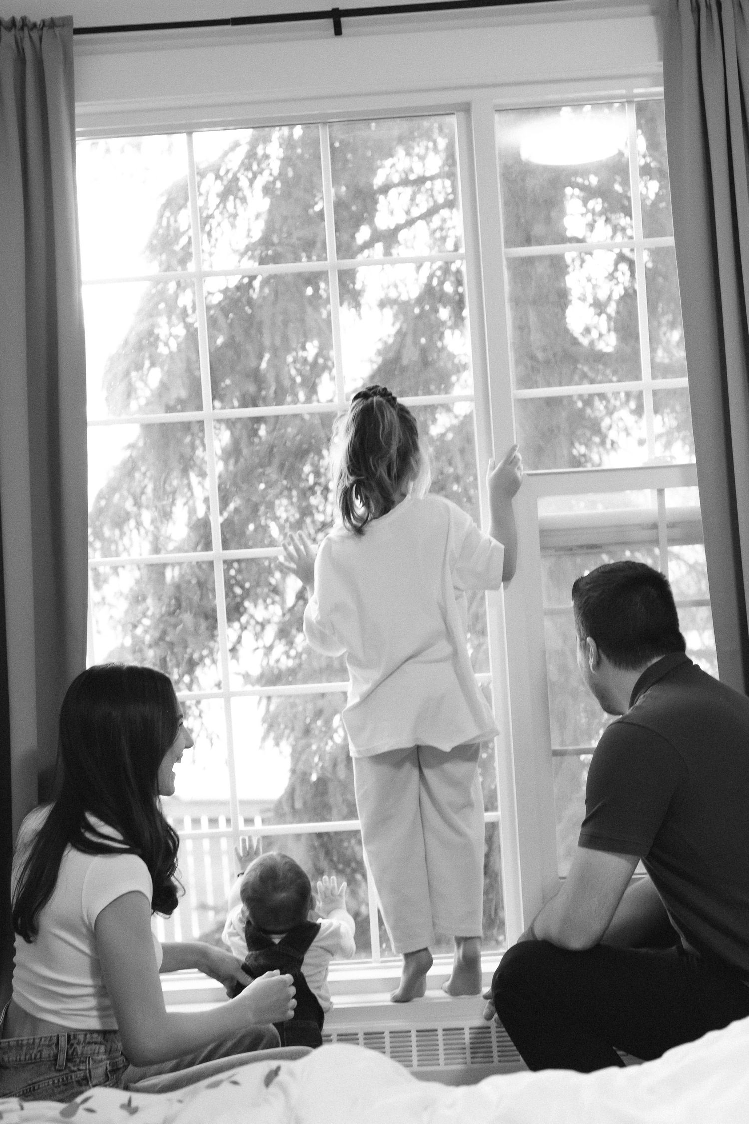 Students sit at desks by windows in a classroom while working on an assignment in black and white.