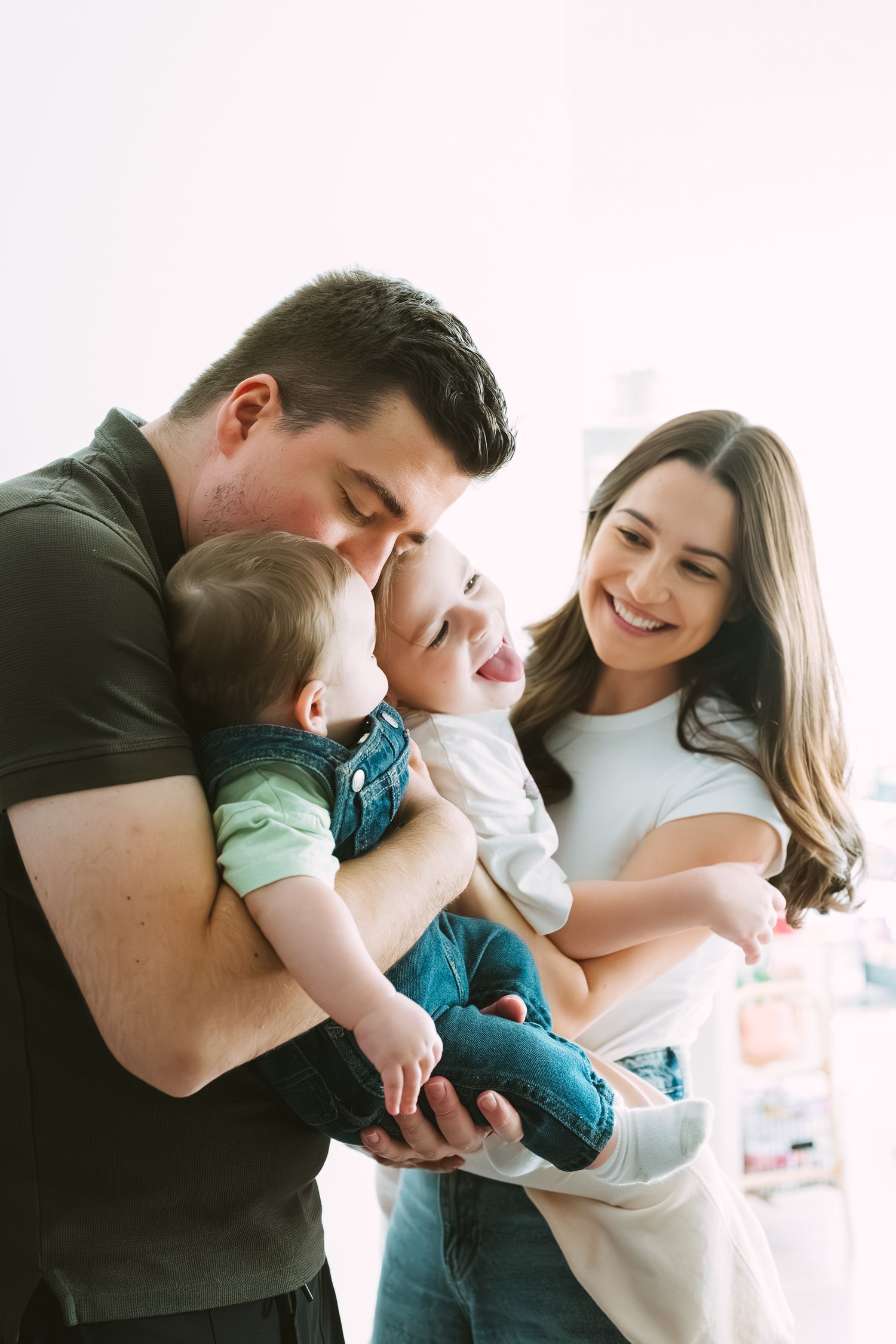 A series of intimate family moments showing parents cuddling with their baby in a bright, minimalist setting.