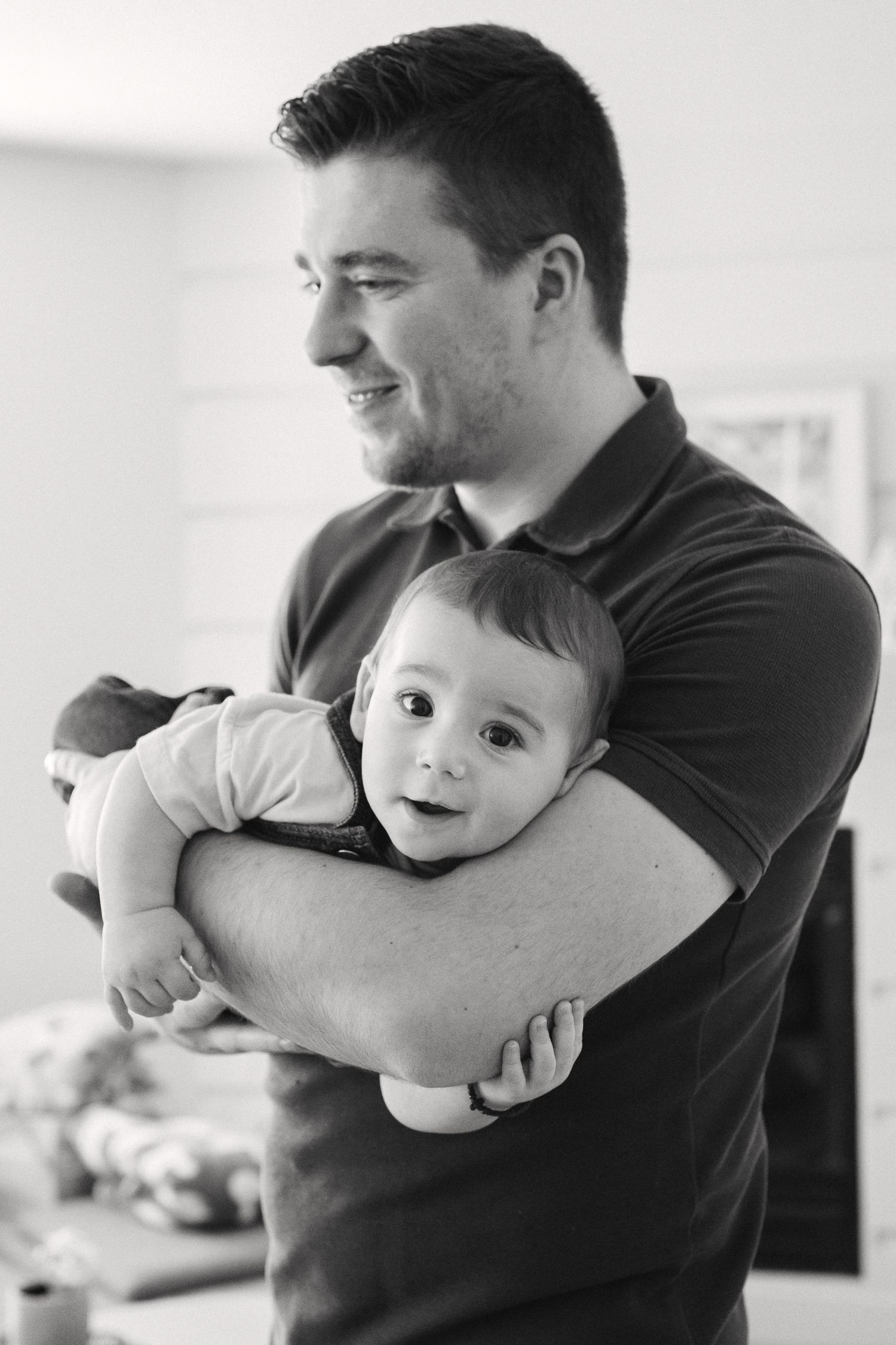 A tender moment captured in black and white as a parent holds a smiling baby.
