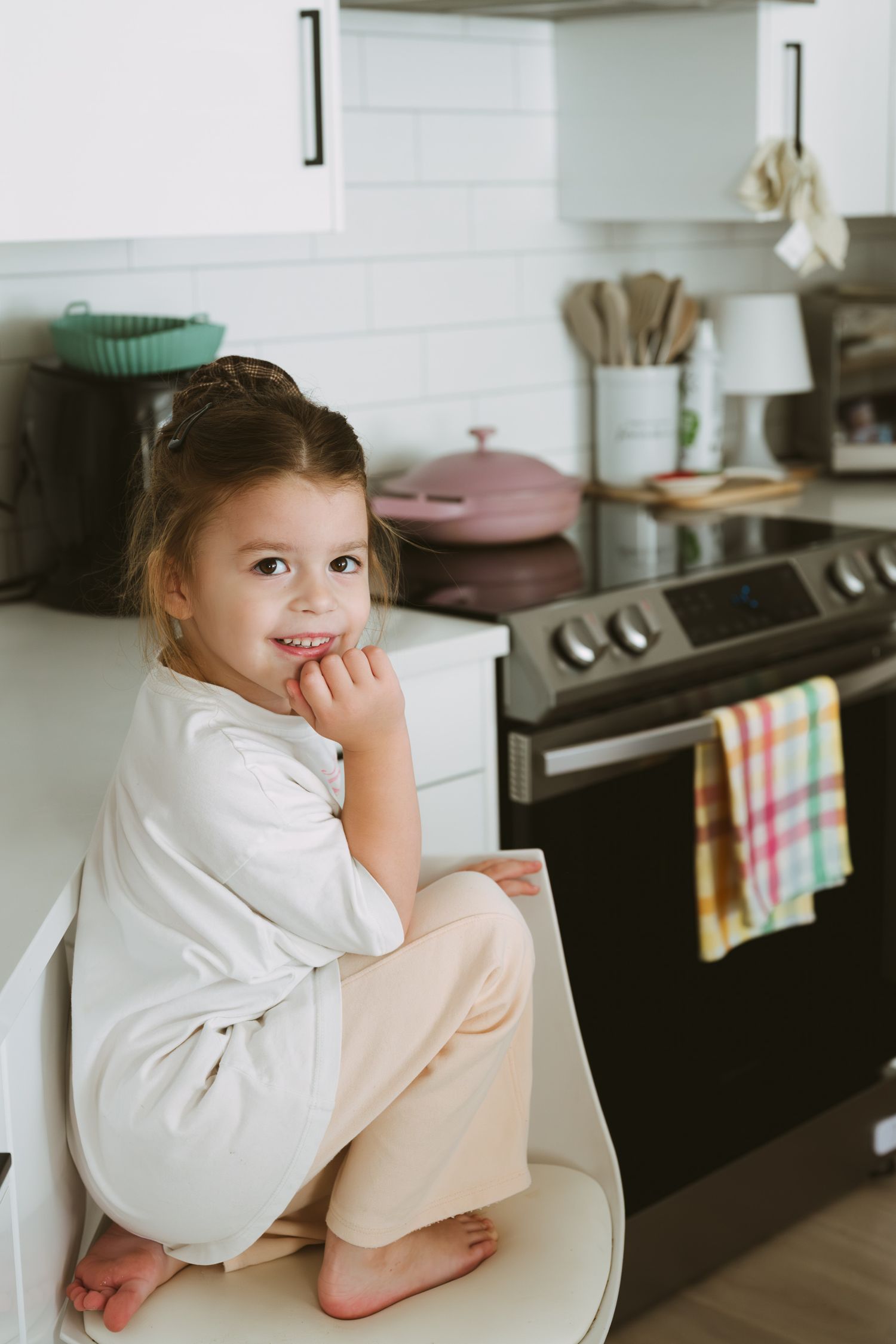 A series of candid shots showing a small child sitting casually on a kitchen counter in a white outfit.