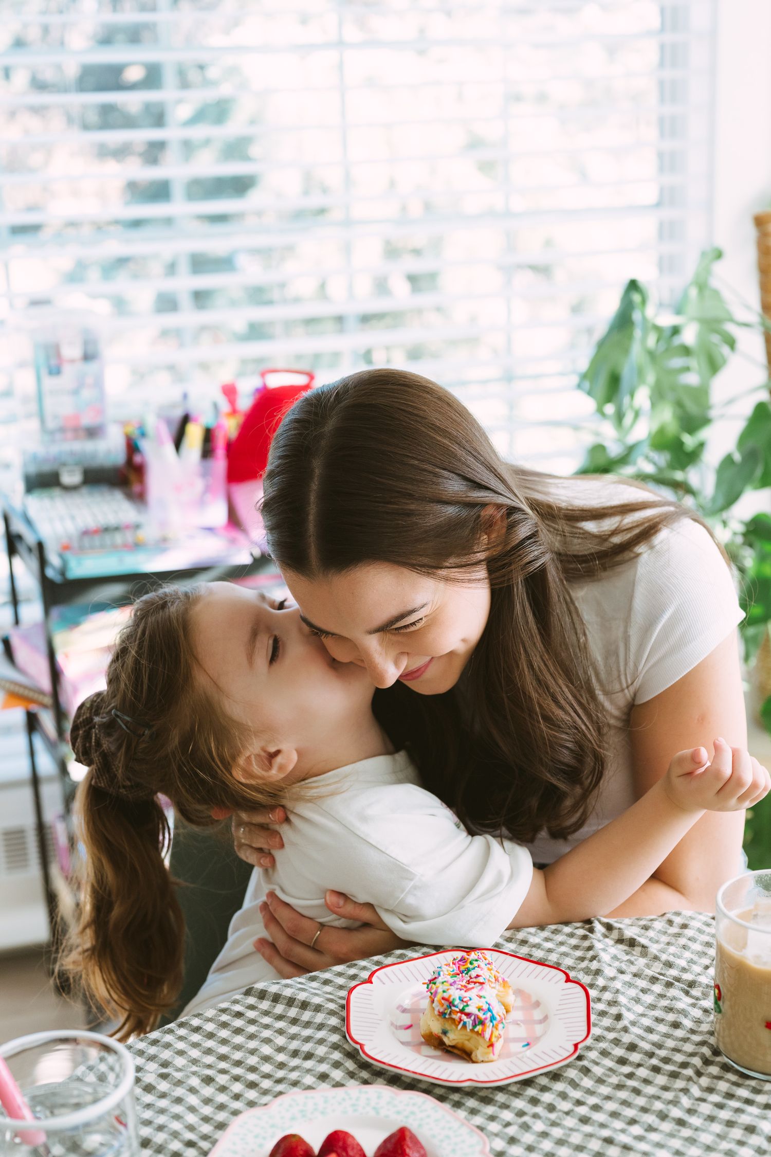 A tender moment shared between parent and child while enjoying a sweet treat at a checkered tablecloth table.