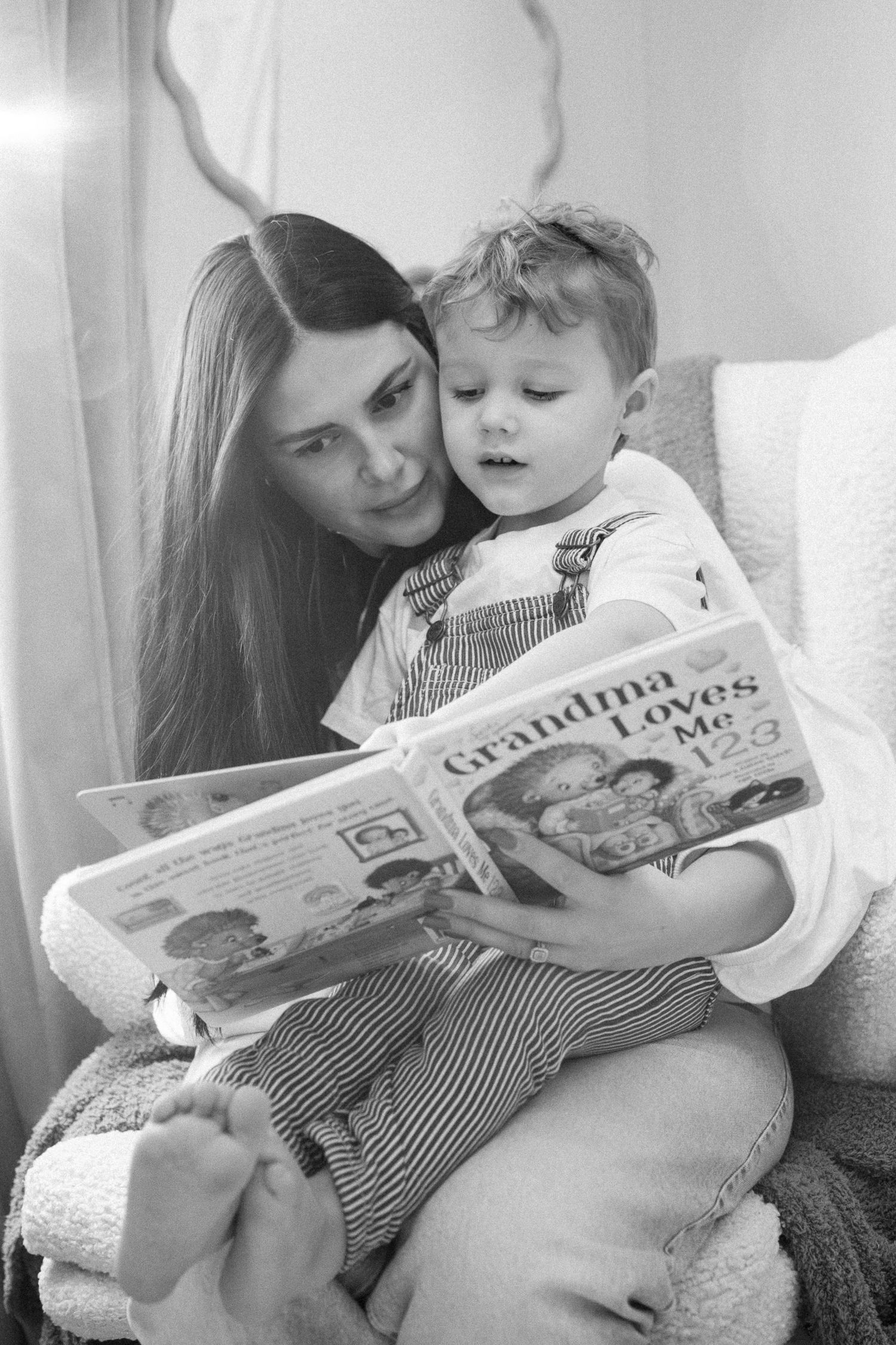 Parent and child reading a picture book together while sitting comfortably.