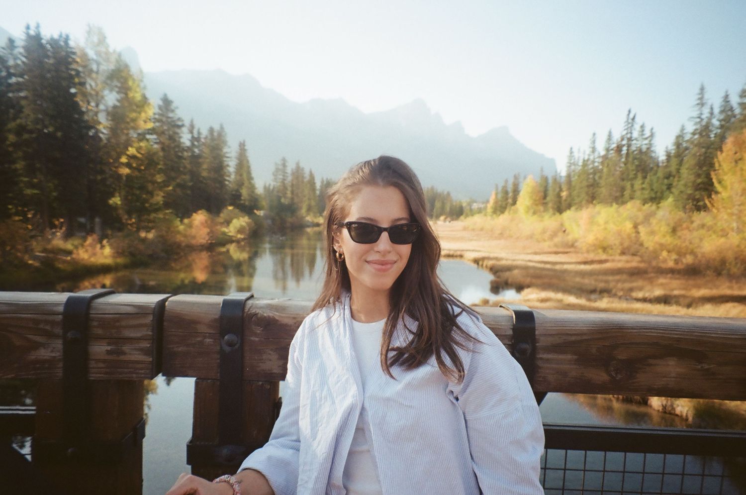 Mountain lake landscape with wooden deck and evergreen forest backdrop.