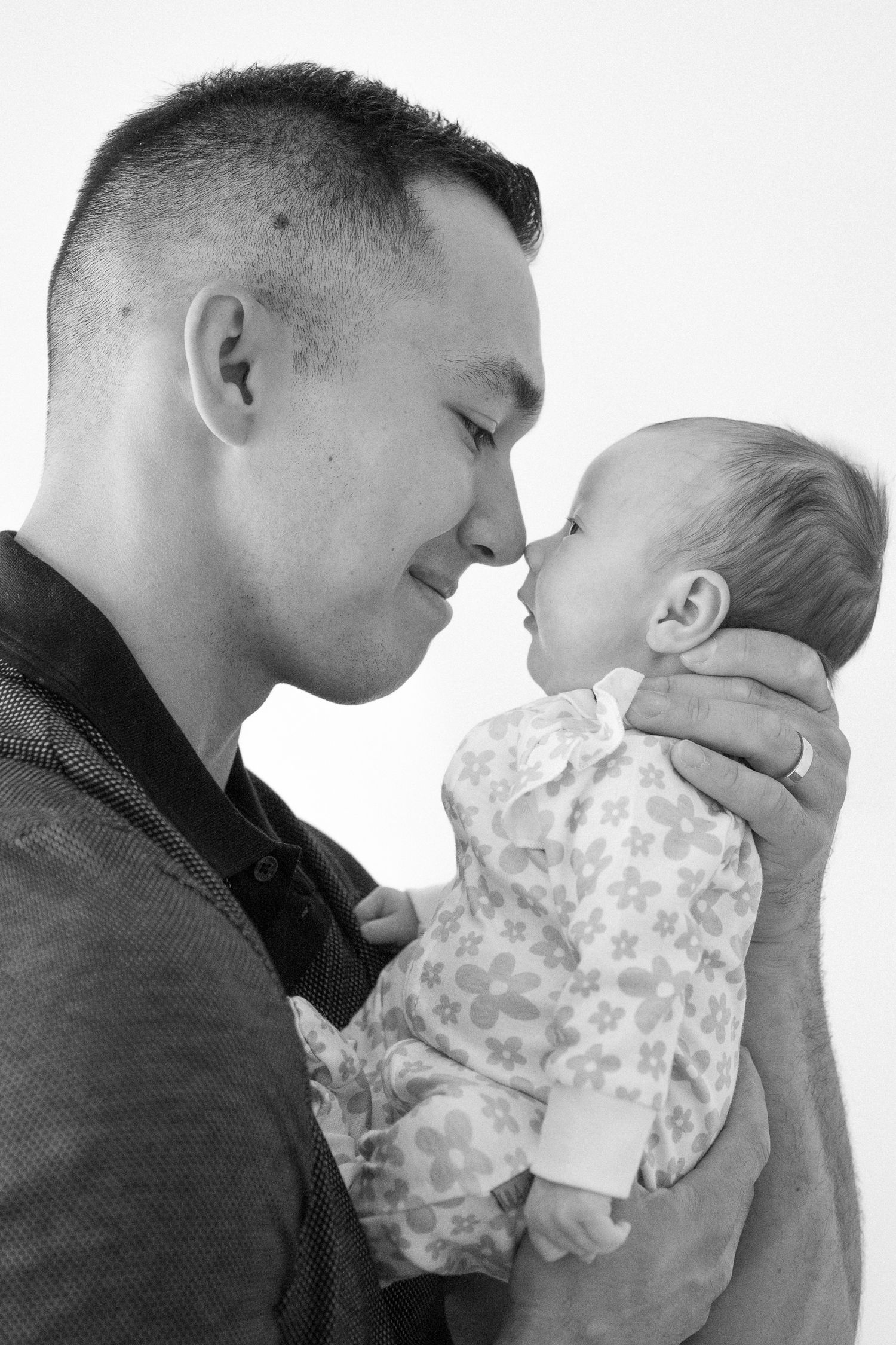 An intimate black and white portrait of a father sharing a tender moment with his baby.