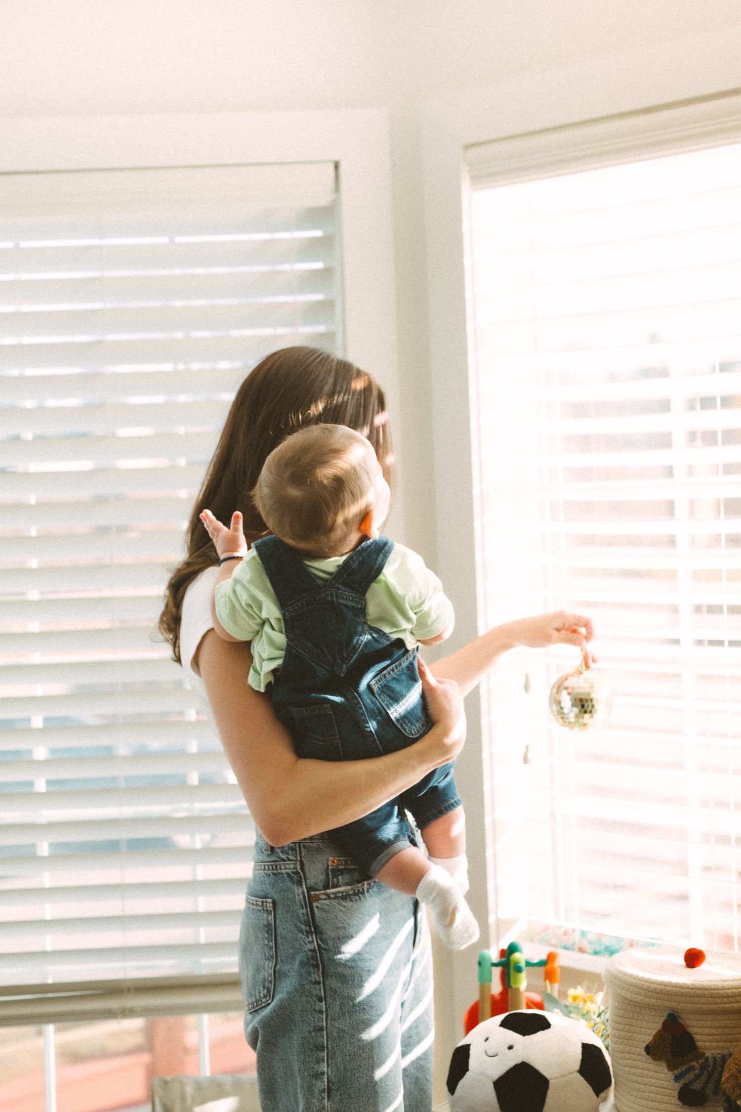 Loving embrace between parent and child in sunlit room with windows.