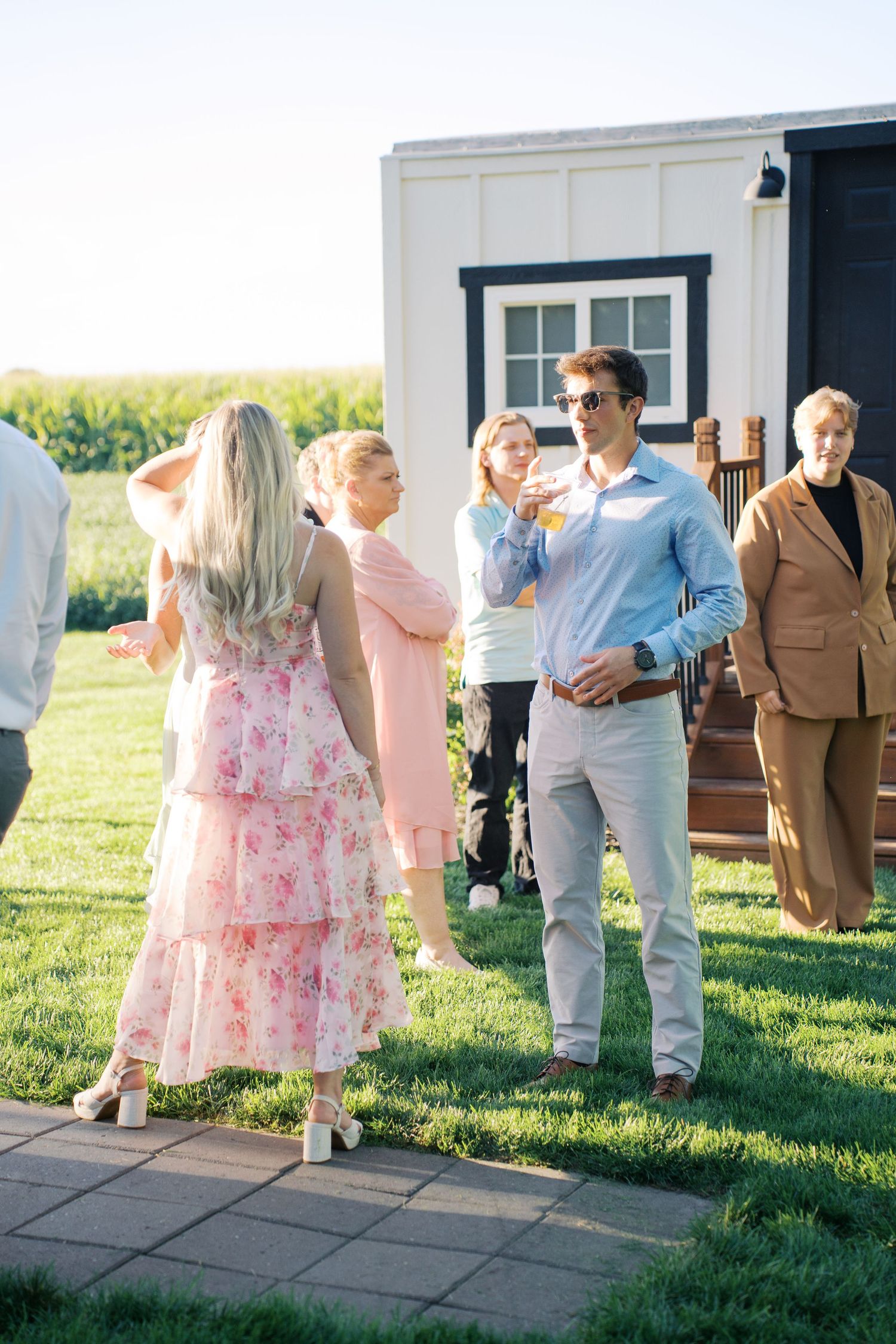 Guests mingle outdoors at an elegant garden party with a white building in the background.