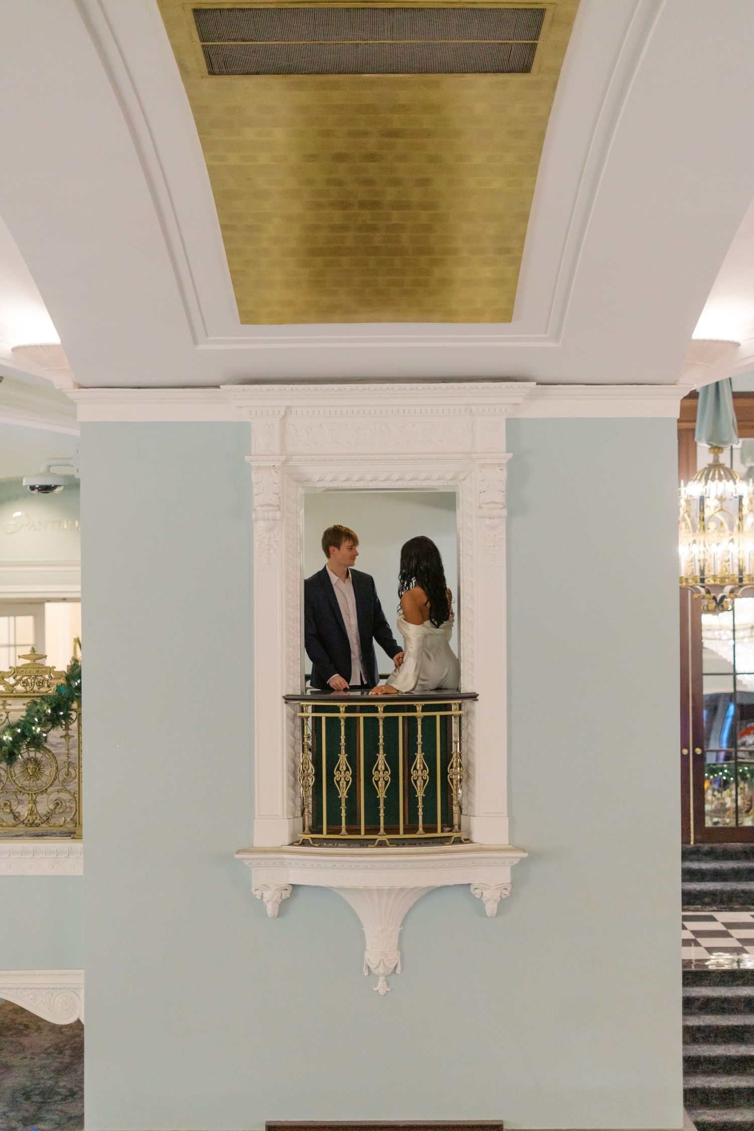 Elegant wedding venue interior with gold ceiling details and mint green walls.