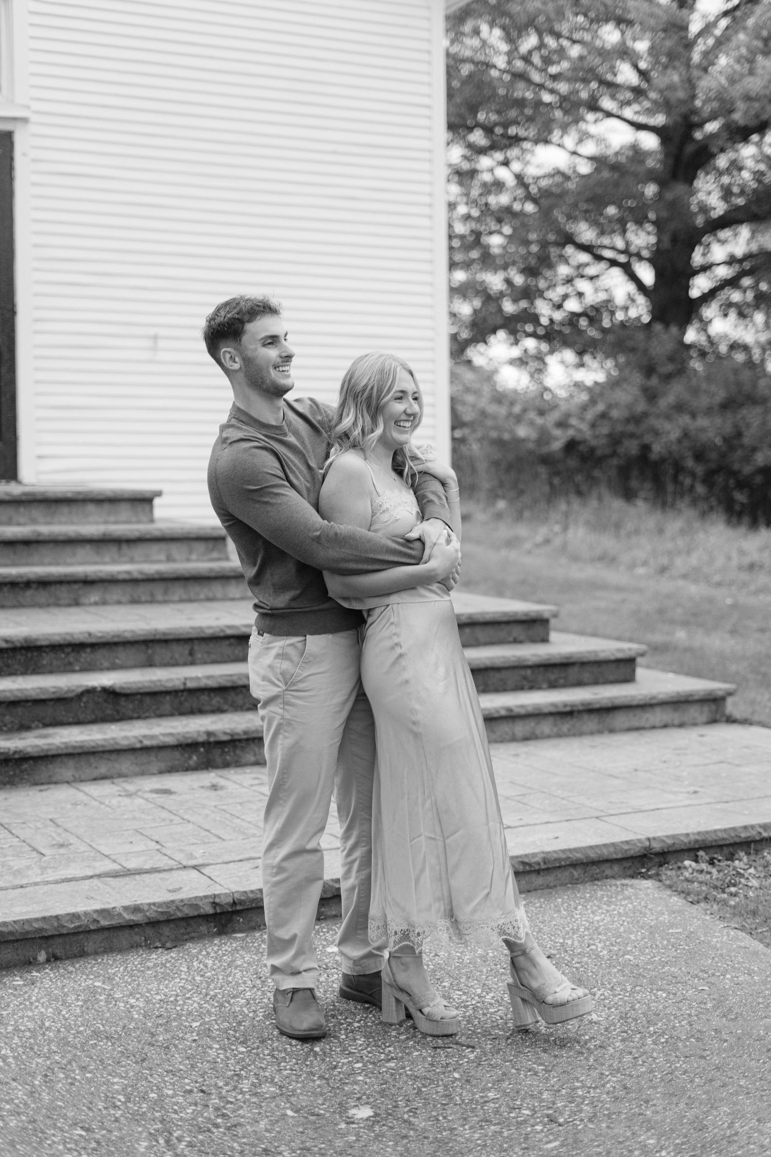 Black and white photo of a couple laughing together on church steps.