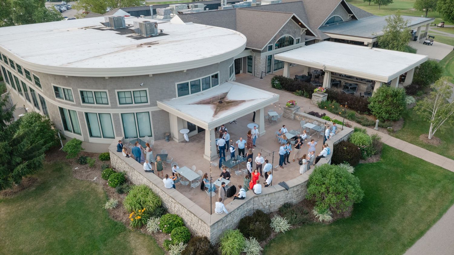 Aerial view of a modern wedding venue with outdoor patio space and gathered guests.