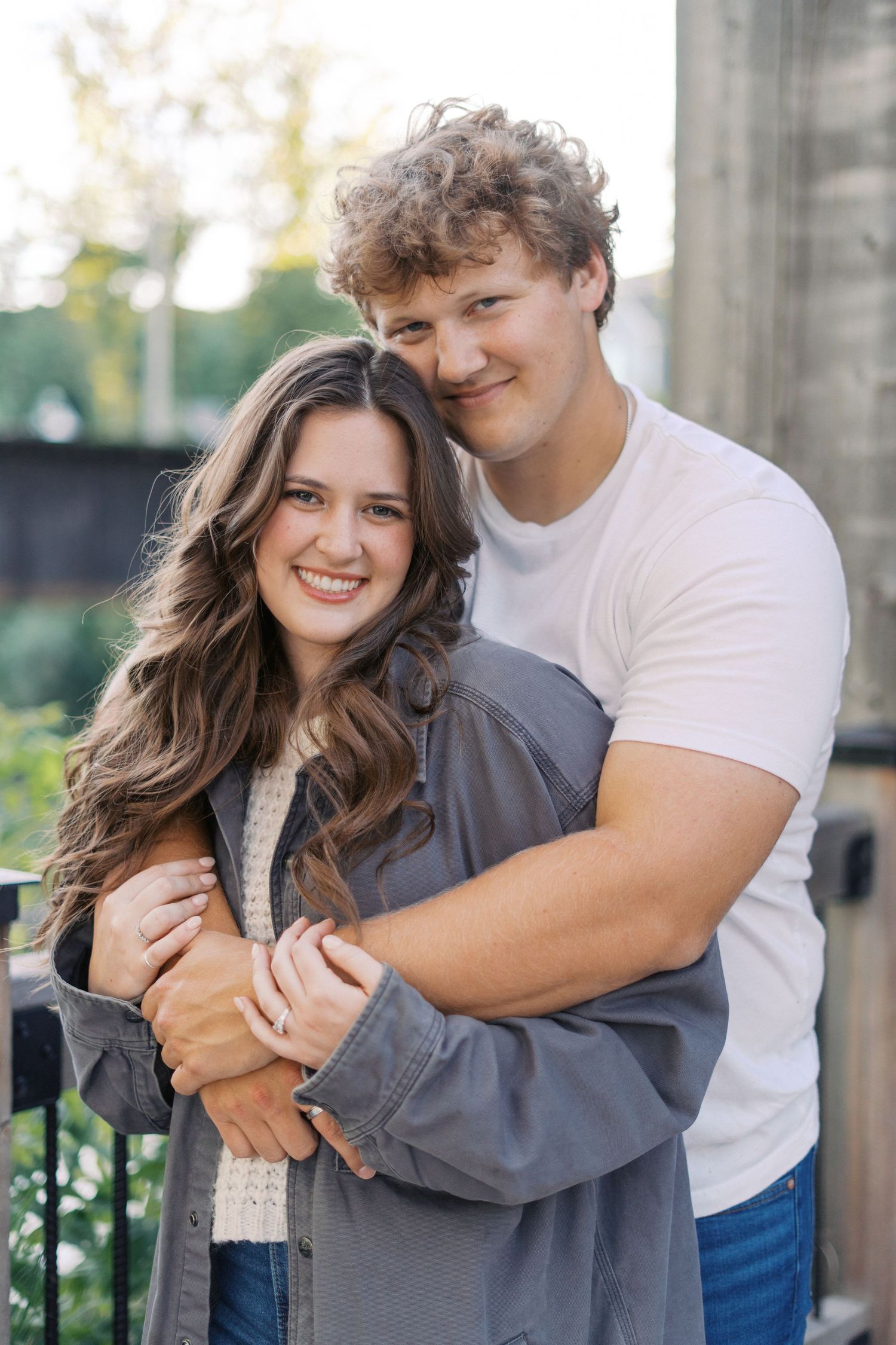 Romantic couple sharing a tender moment while standing against concrete pillars.