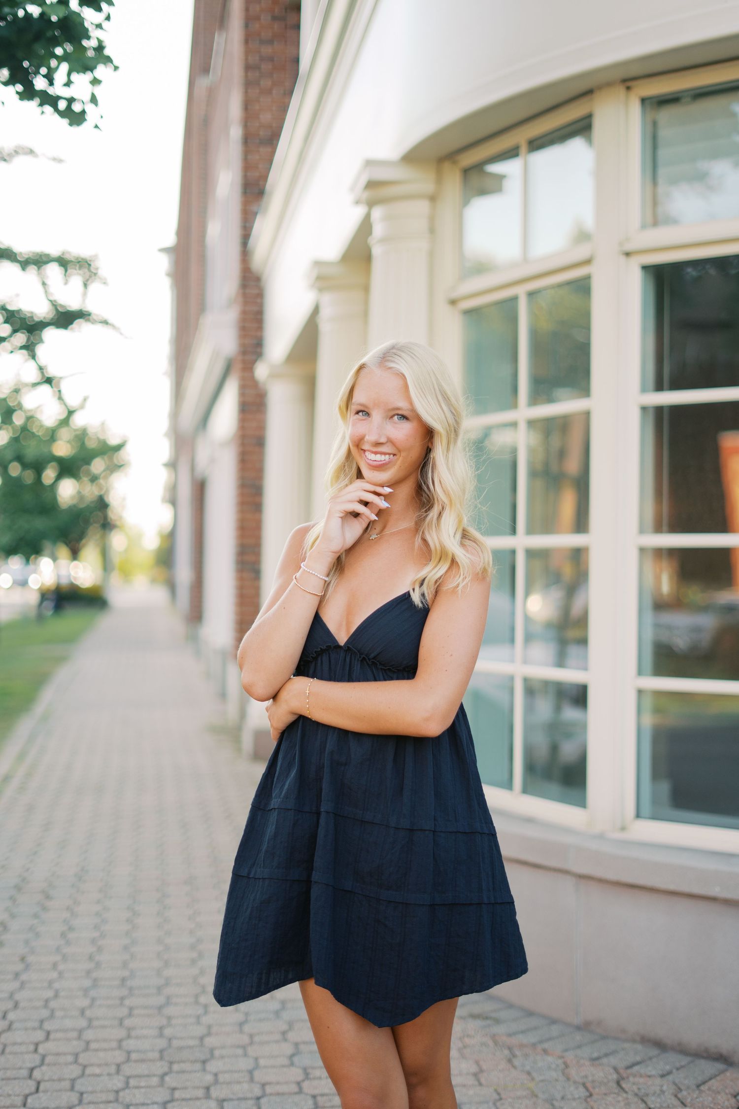 Casual outdoor portraits in navy dress along brick building walkway.