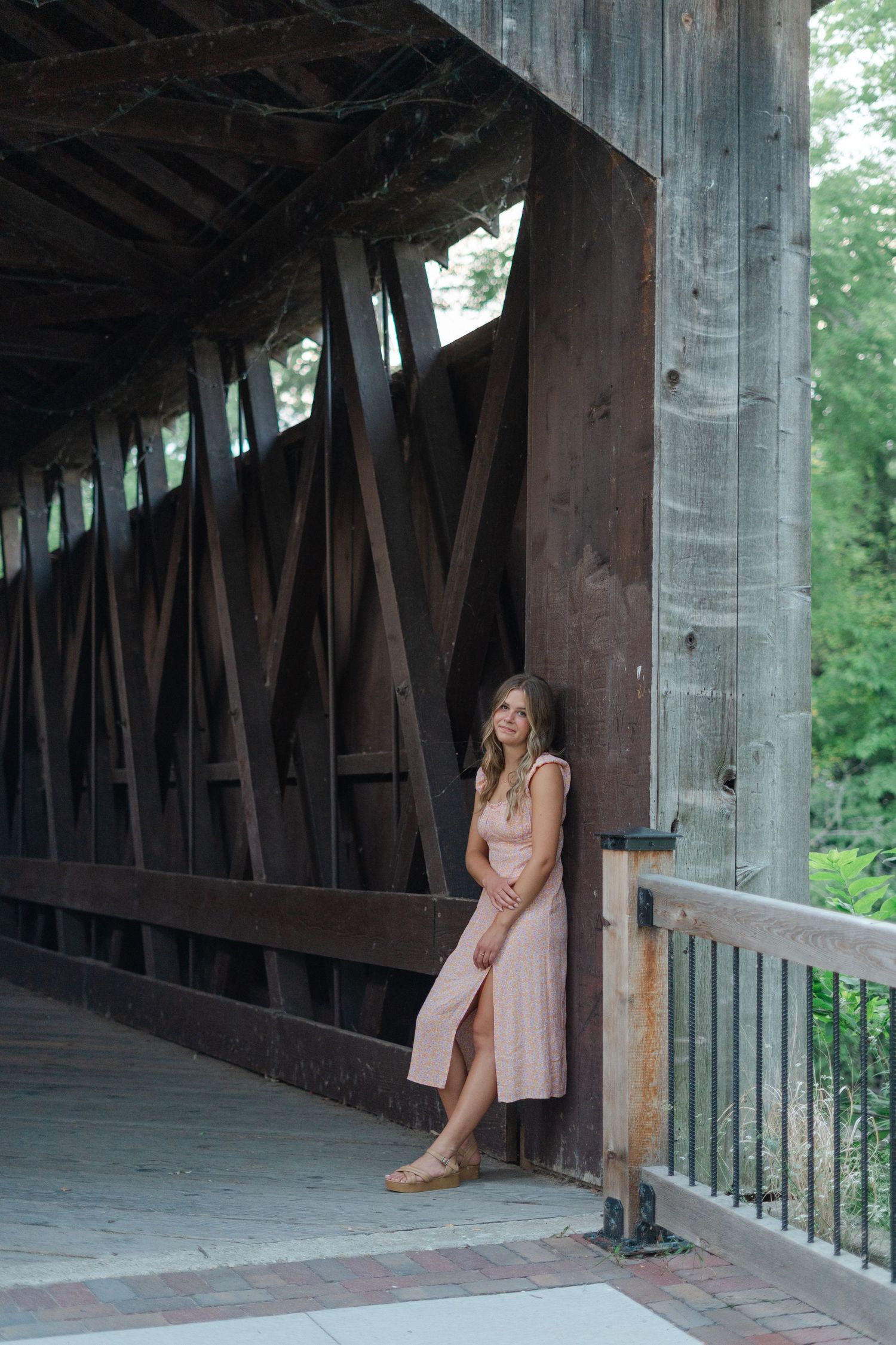 Artistic portrait under a covered wooden bridge with rustic architectural details.